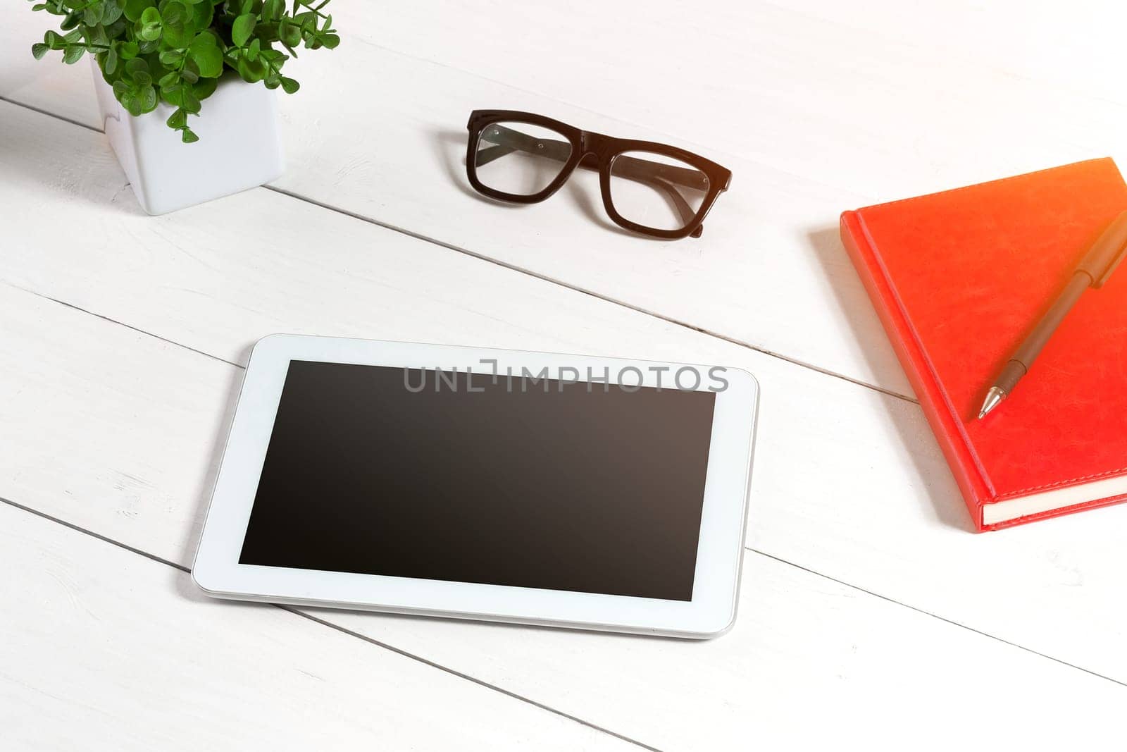 Stylish minimalistic workplace with tablet and notebook and glasses in flat lay style. White background. Top view. Copy space. sun flare