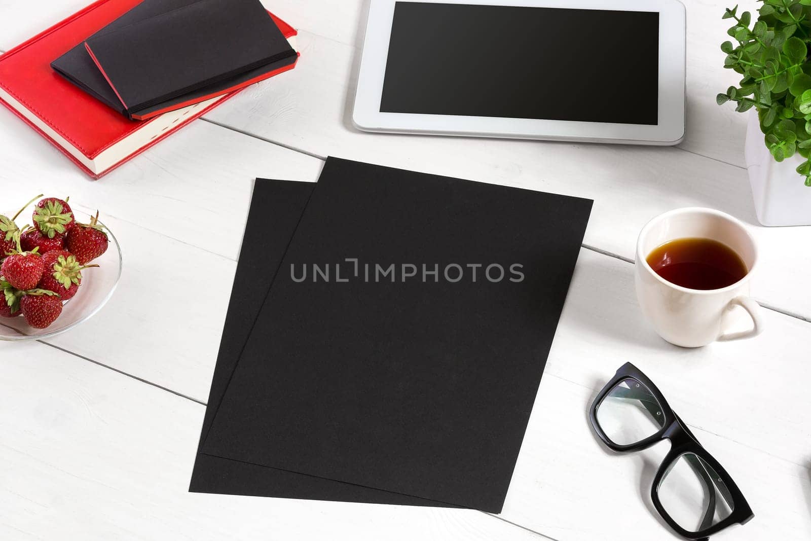 Stylish minimalistic workplace with tablet and notebook and glasses in flat lay style. White background. Top view. Copy space