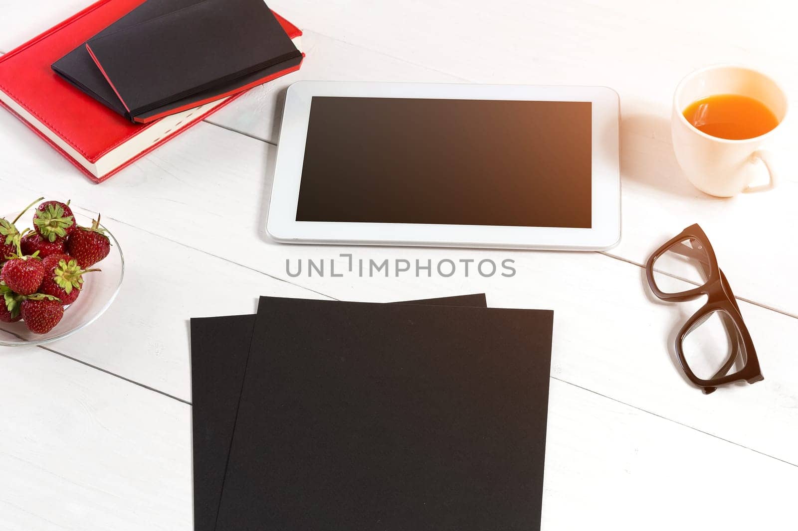 Stylish minimalistic workplace with tablet and notebook and glasses in flat lay style. White background. Top view. Copy space. sun flare