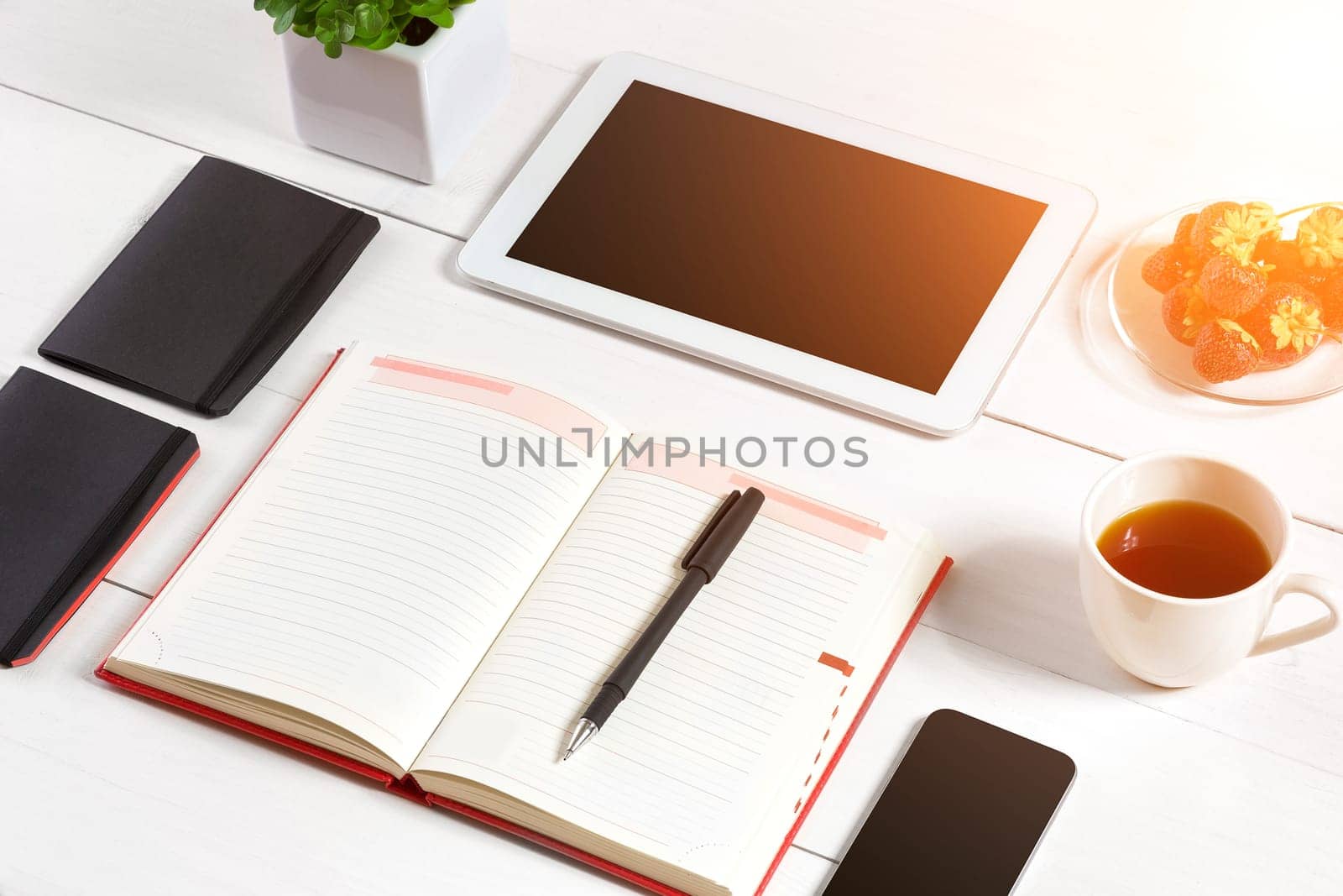 Office table desk with set of supplies, white blank notepad, cup, pen, tablet, glasses, flower on white background. Top view by nazarovsergey