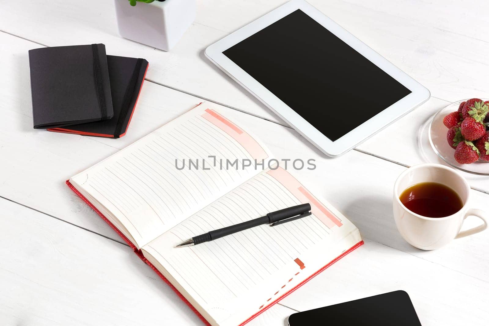 Stylish minimalistic workplace with tablet and notebook and glasses in flat lay style. White background. Top view. Copy space