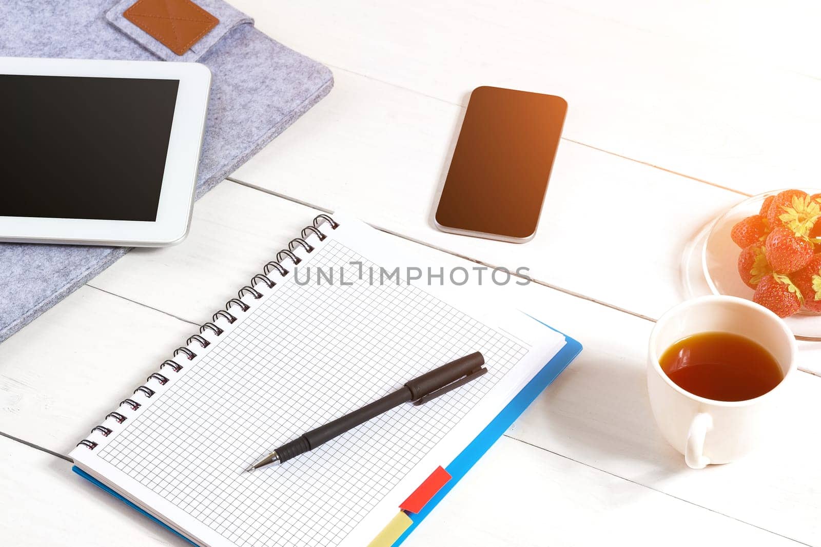 Stylish minimalistic workplace with tablet and notebook and glasses in flat lay style. White background. Top view. Copy space. sun flare