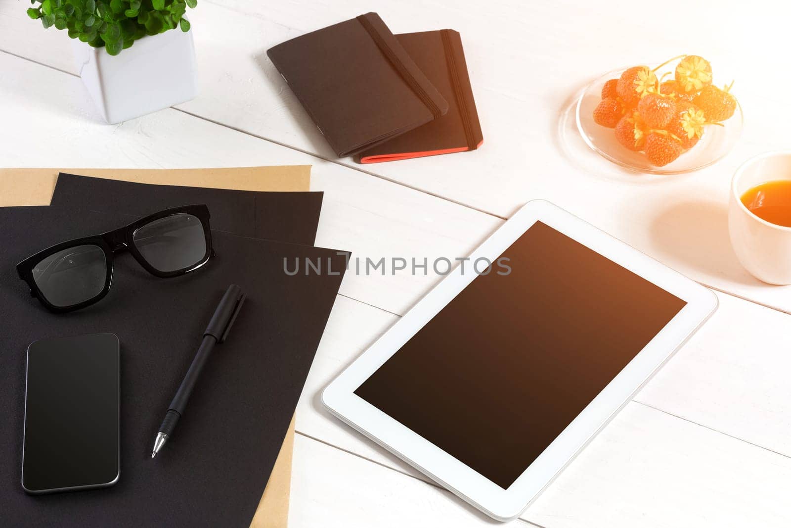 Modern workplace with digital tablet computer and mobile phone, cup of coffee, pen and empty sheet of paper. Top view and copy space for text. sun flare