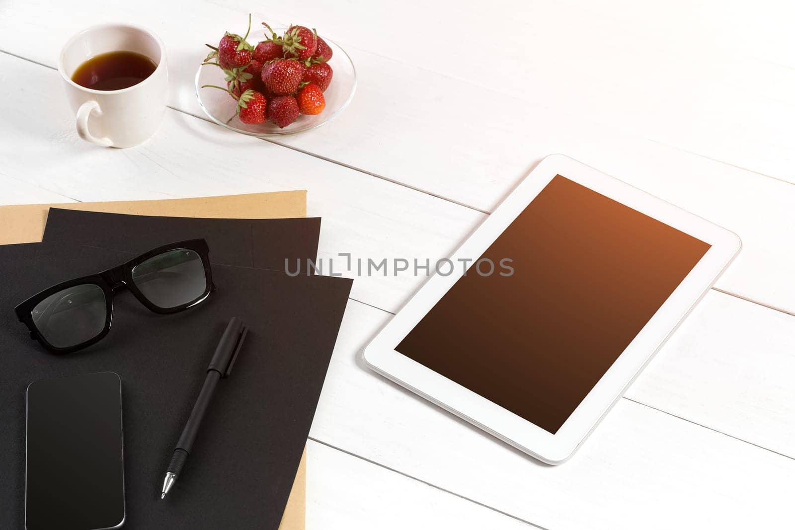 Modern workplace with digital tablet computer and mobile phone, cup of coffee, pen and empty sheet of paper. Top view and copy space for text. sun flare