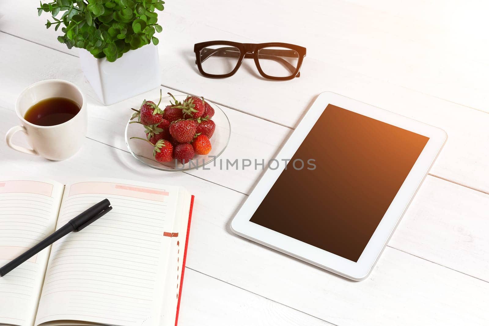 Office table desk with set of supplies, white blank notepad, cup, pen, tablet, glasses, flower on white background. Top view by nazarovsergey