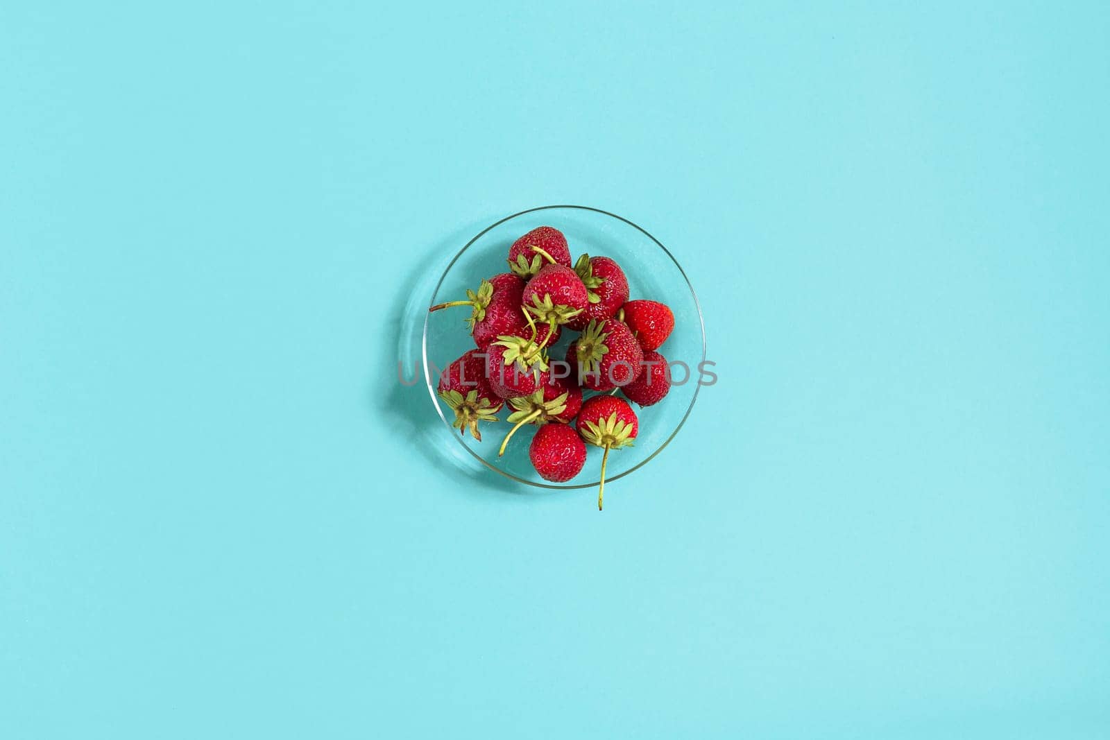 Ripe strawberries on the saucer isolated on mint background. Top view. Copy space. Still life mockup flat lay