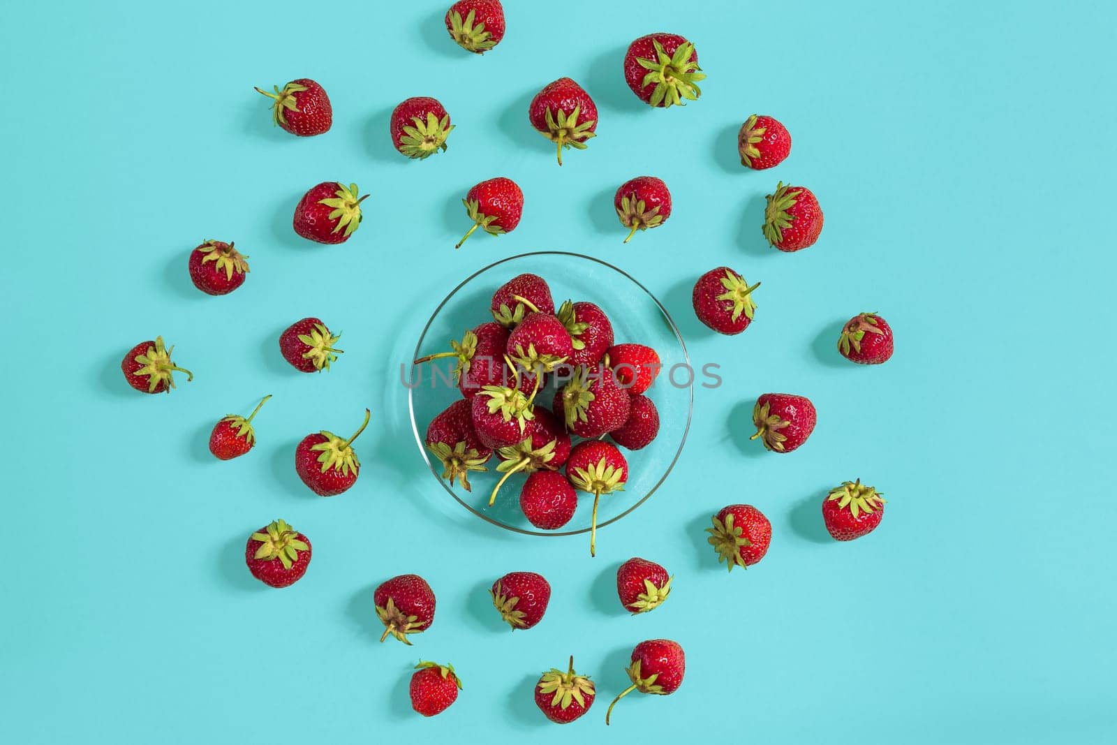 Ripe strawberries on the saucer isolated on mint background. Top view. Copy space. Still life mockup flat lay