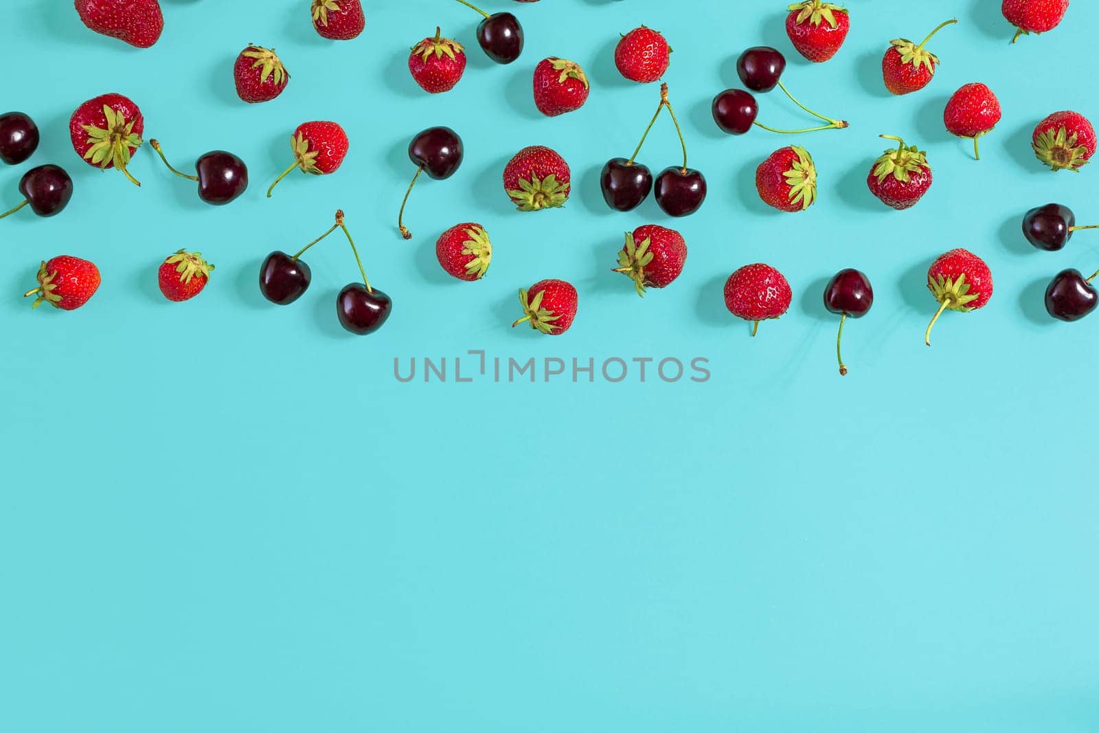 Fresh cherries and strawberries on mint background, top view. Copy space. Still life mockup flat lay