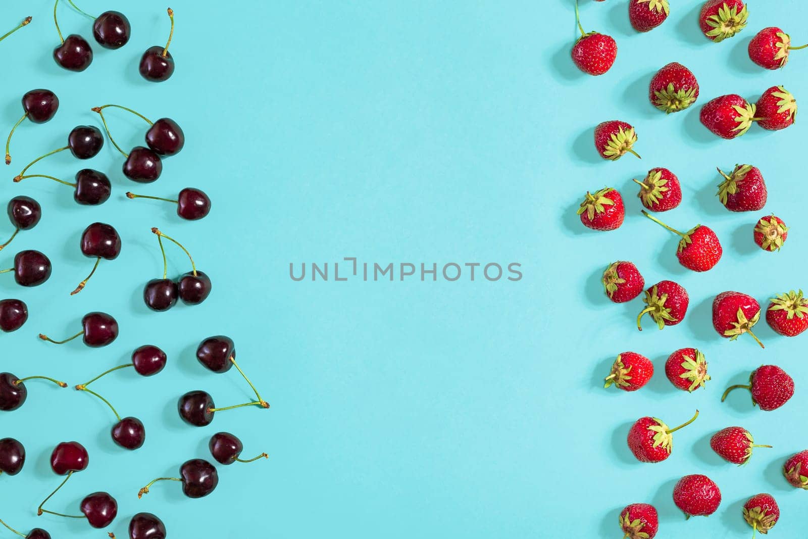 Fresh cherries and strawberries on mint background, top view. Copy space. Still life mockup flat lay