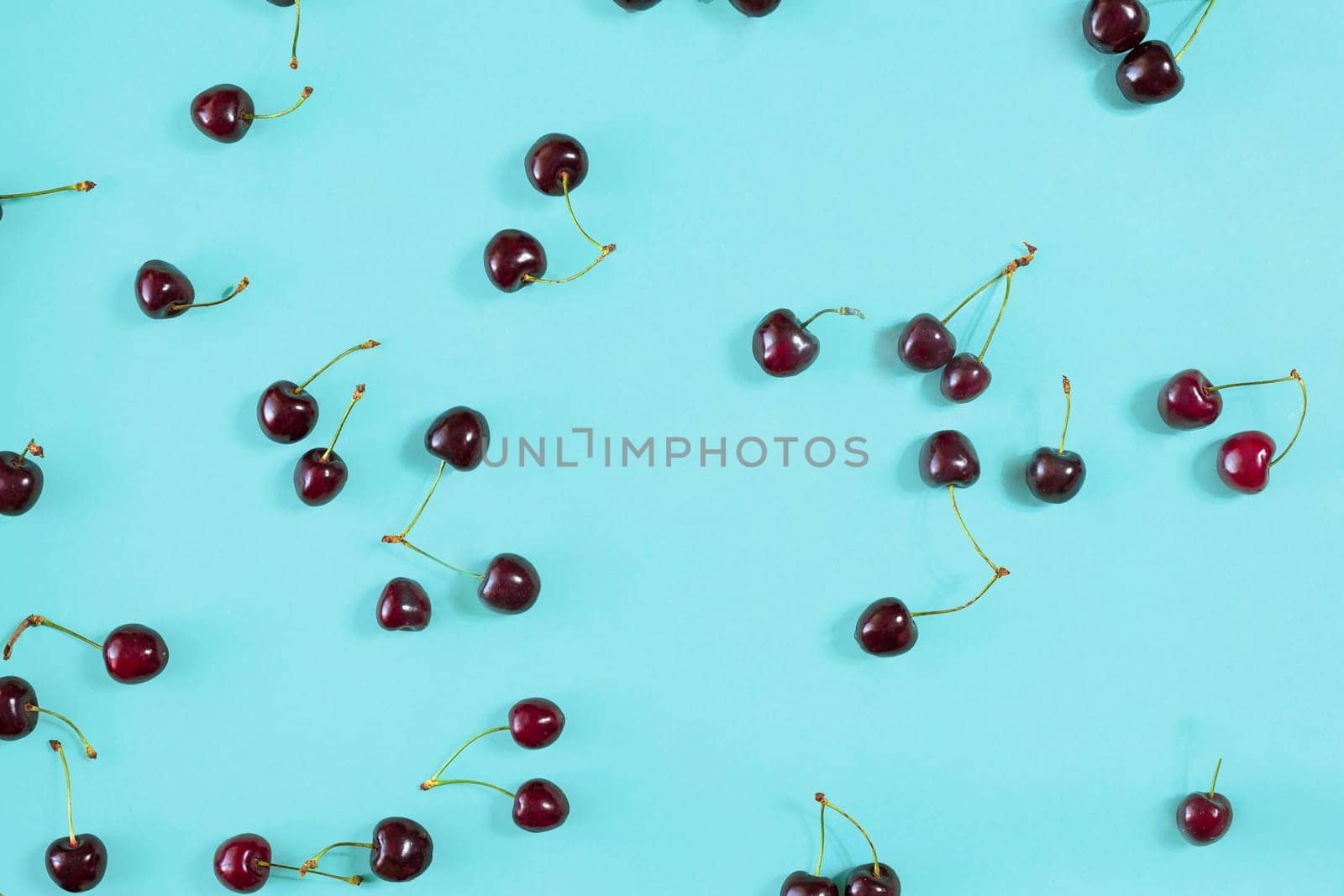 Fresh juicy cherries on mint background, top view. Copy space. Still life mockup flat lay