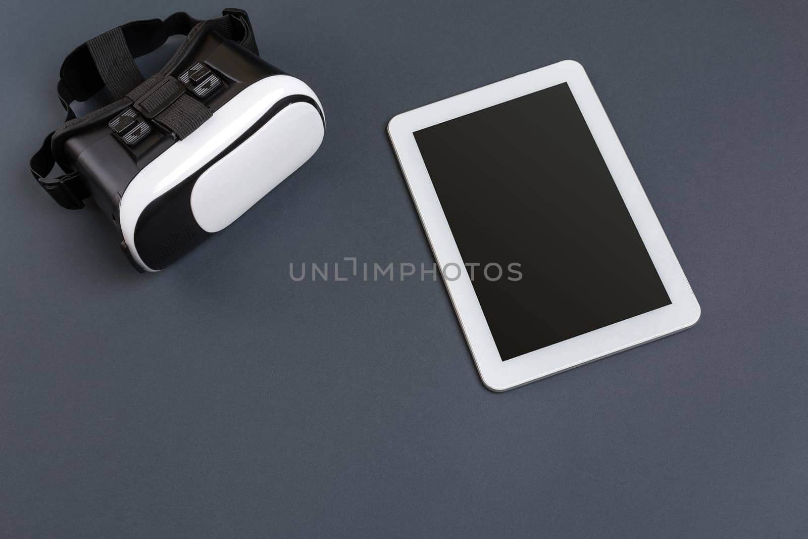 Virtual reality glasses and tablet on a gray background. Top view. Copy space