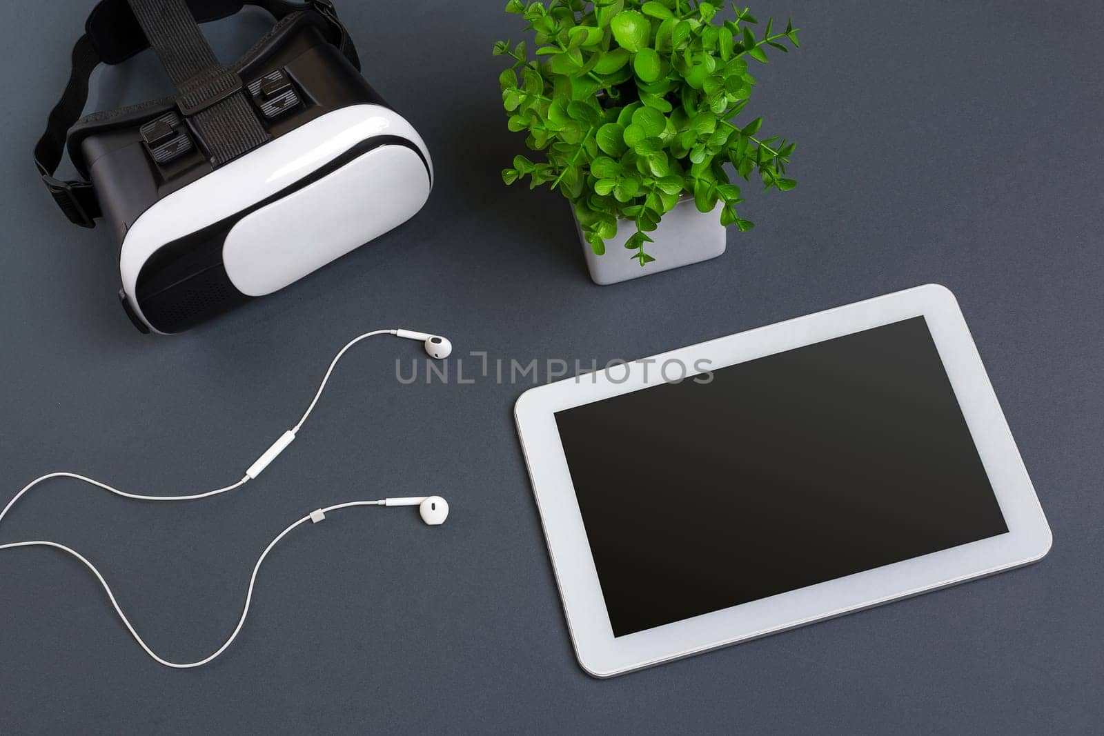 Virtual reality glasses and tablet with headphones on a gray background. Top view. Copy space