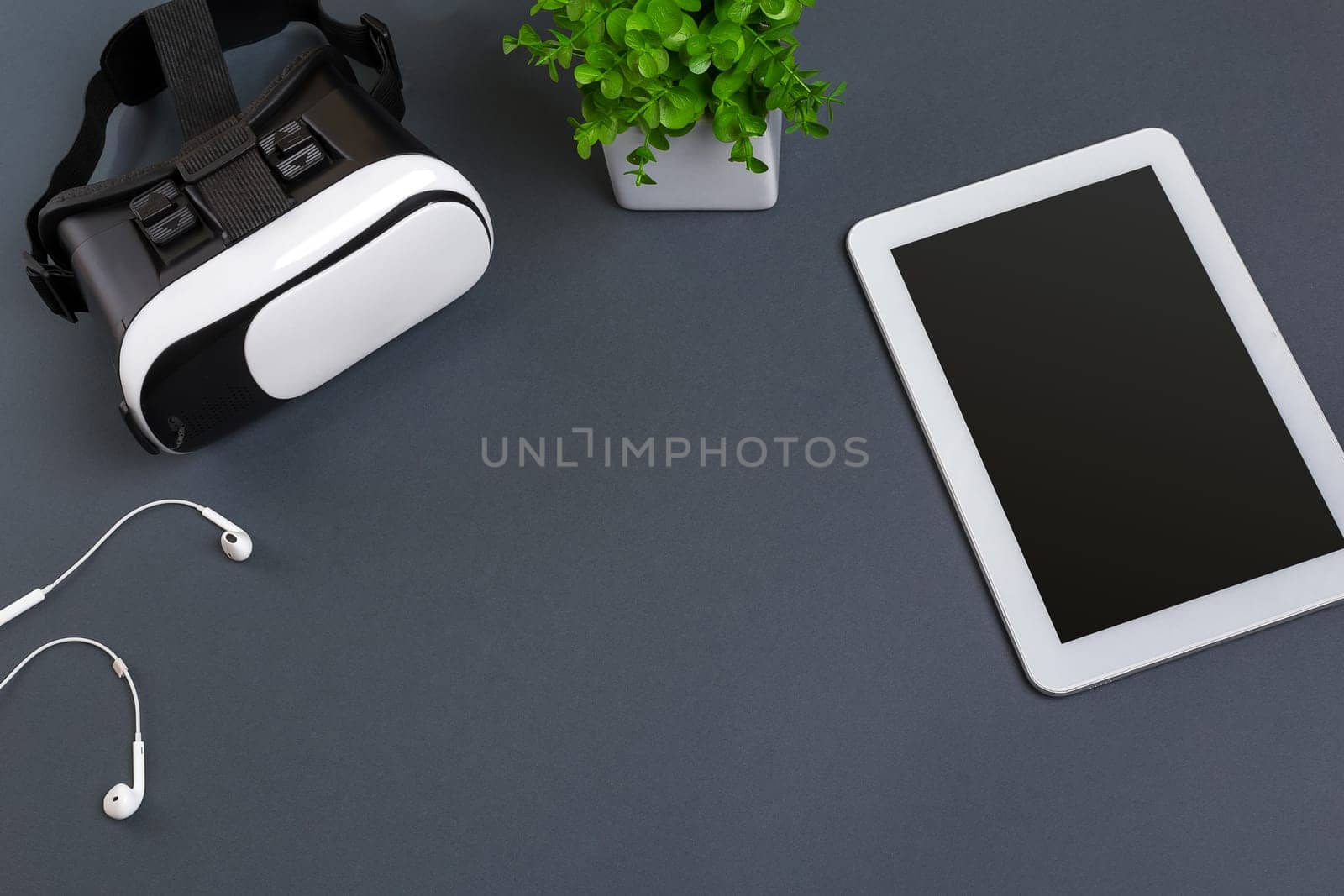 Virtual reality glasses and tablet with headphones on a gray background. Top view. Copy space