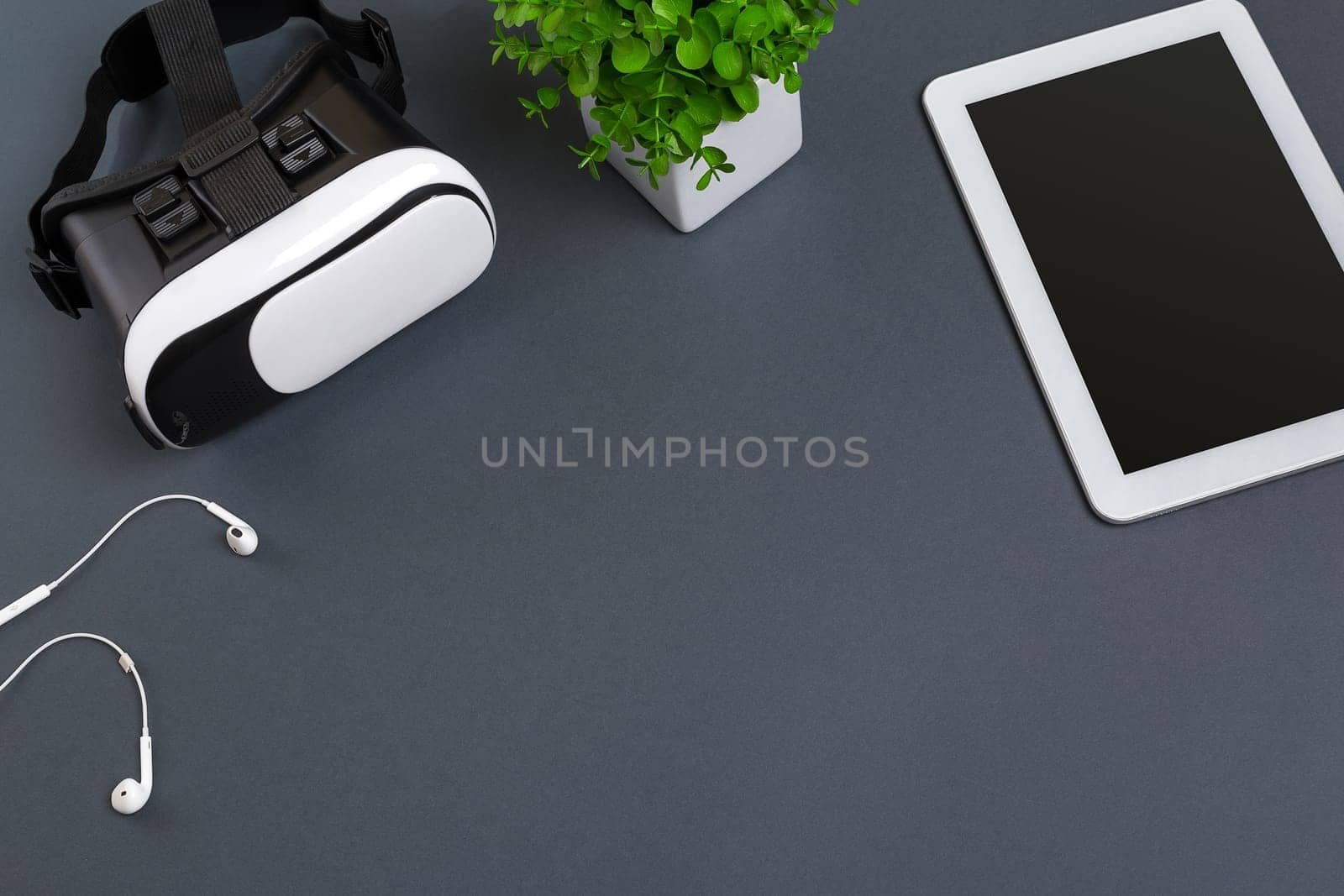 Virtual reality glasses and tablet with headphones on a gray background. Top view. Copy space