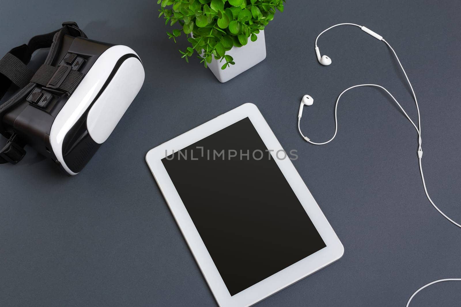 Virtual reality glasses and tablet with headphones on a gray background. Top view. Copy space