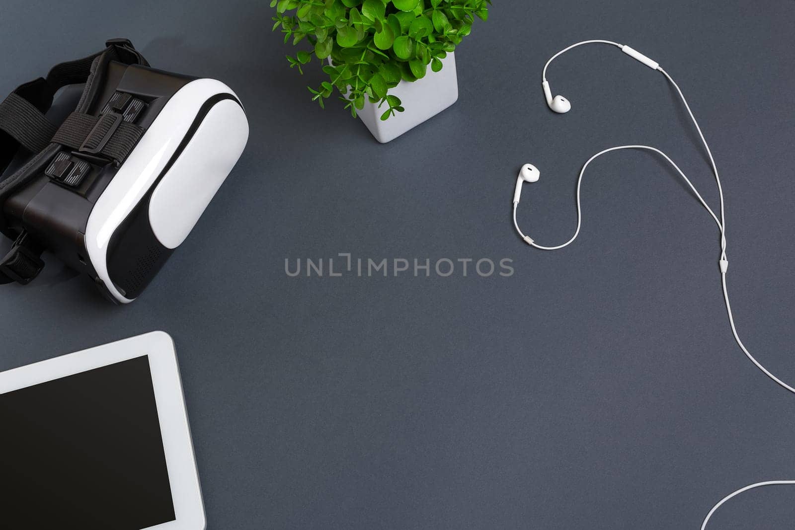 Virtual reality glasses and tablet with headphones on a gray background. Top view. Copy space