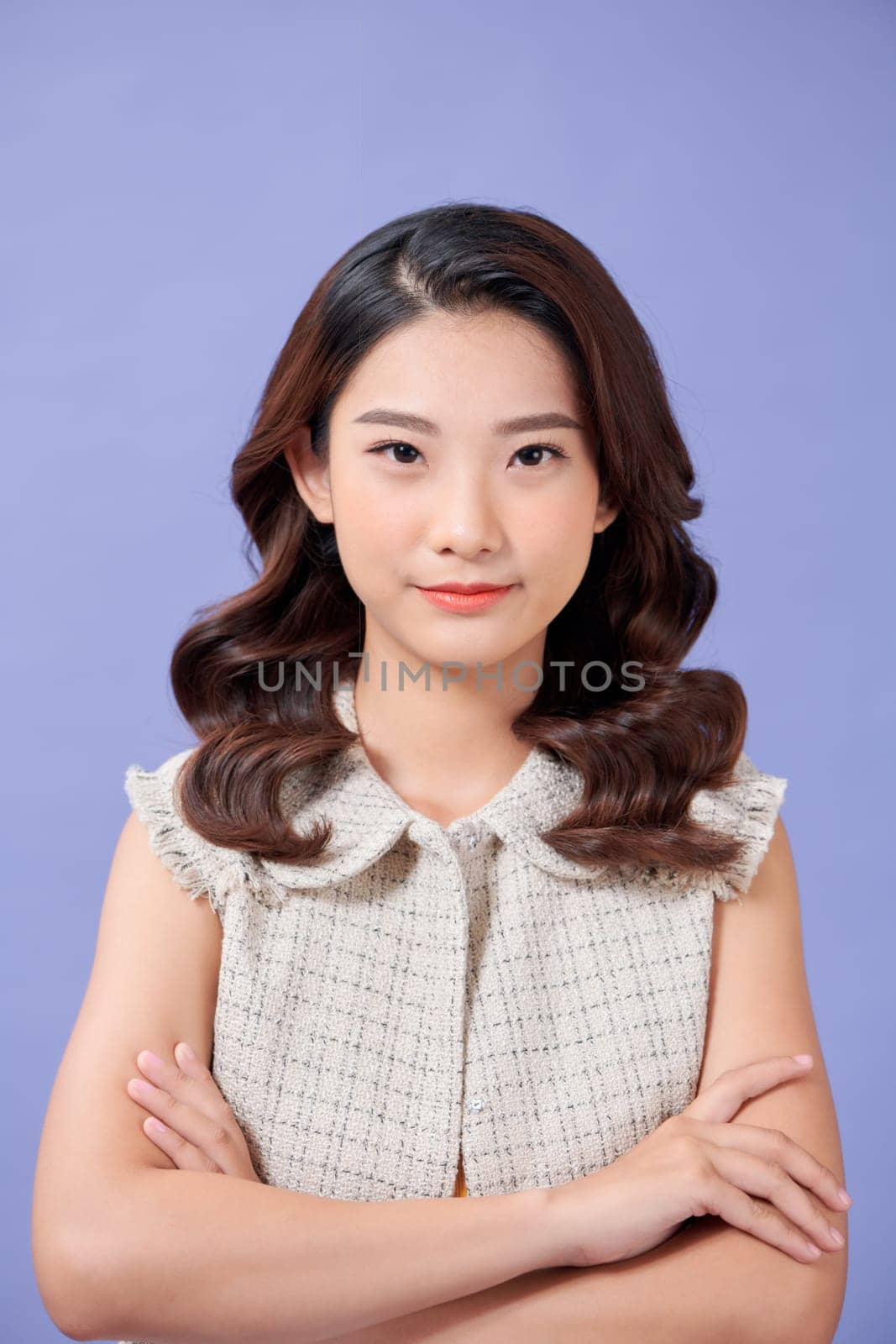 Happy successful woman smiling pleased  and looking confident, standing against purple