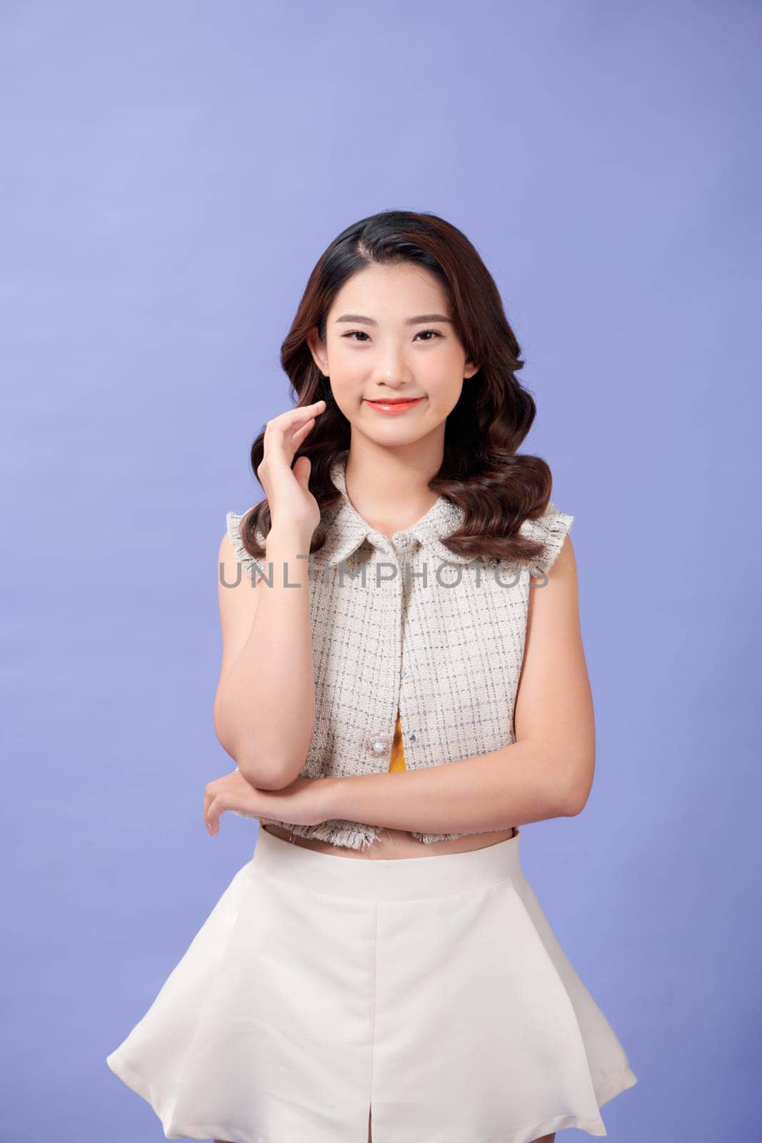 Portrait of a beautiful smiling young girl in casual clothes standing isolated over purple background