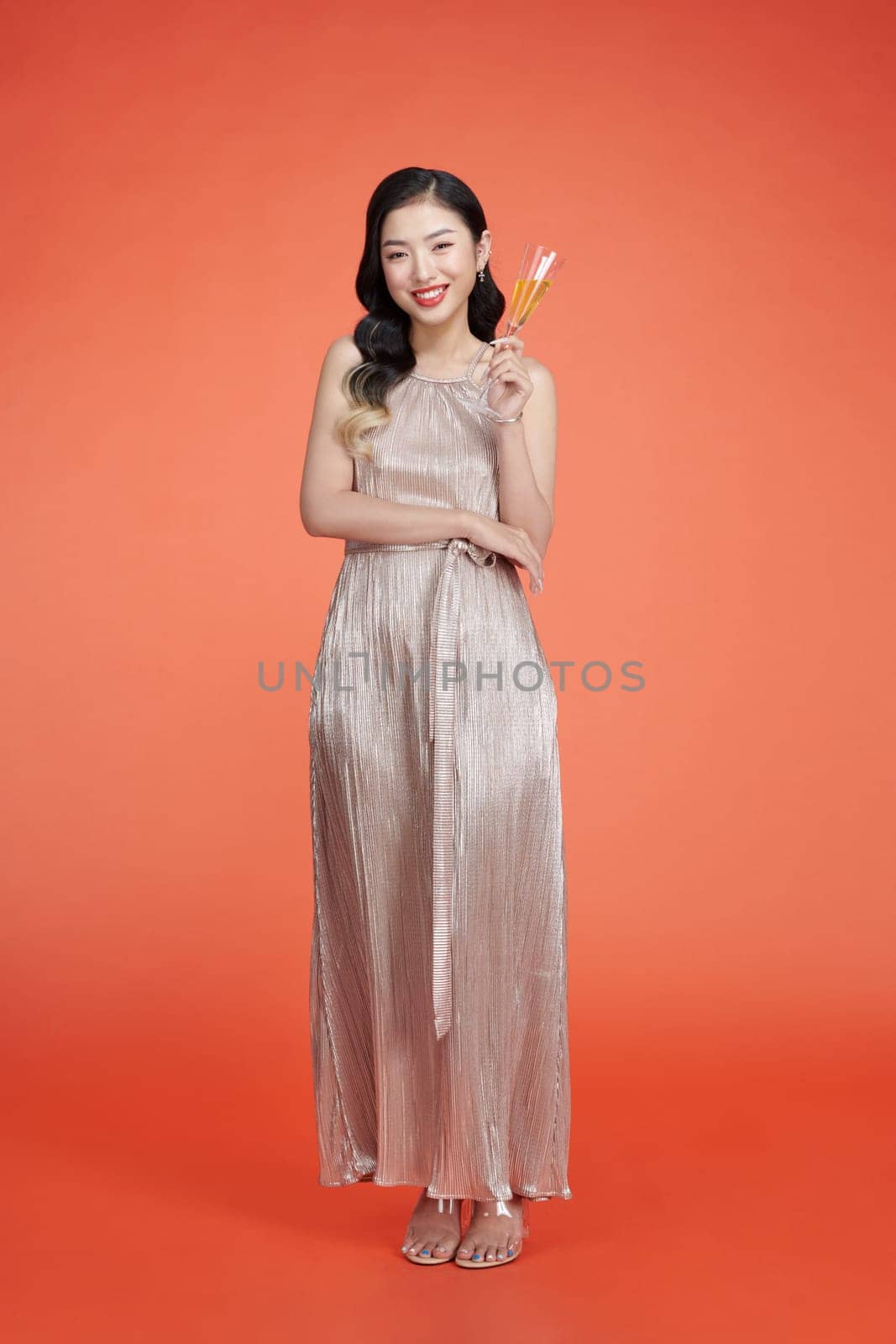 Smiling woman in elegant sequin dress holding glass of champagne and enjoying new year party