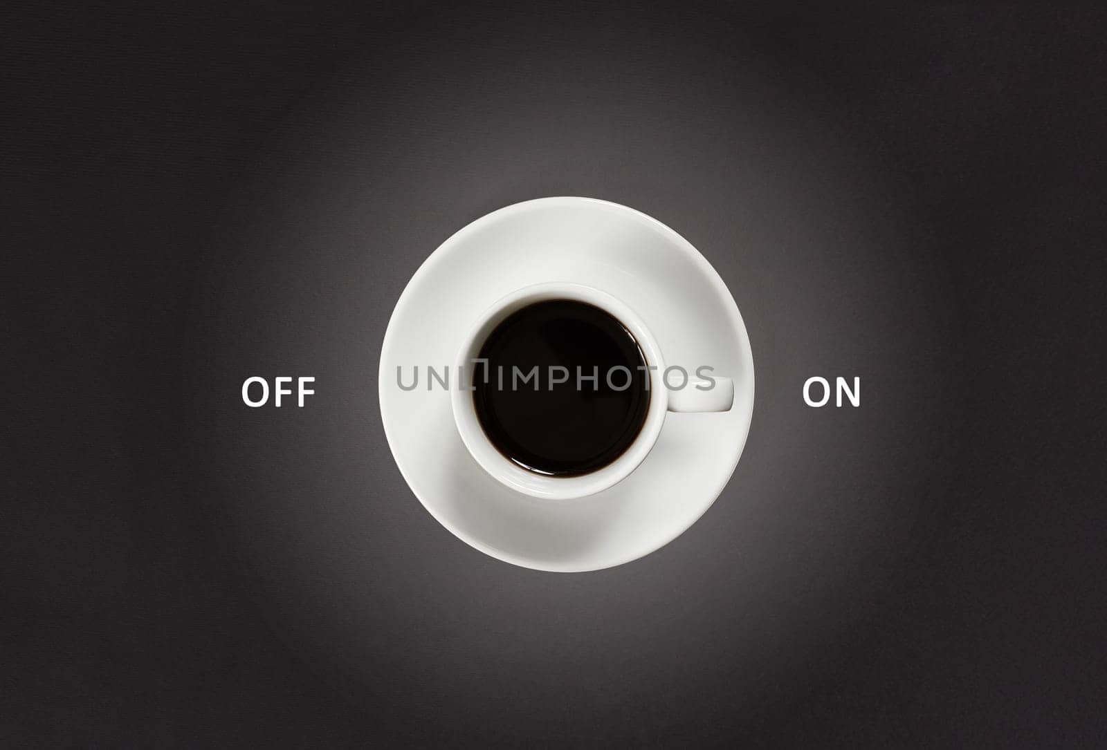 Coffee in white cup with a lettering on and off on black slate background, top view