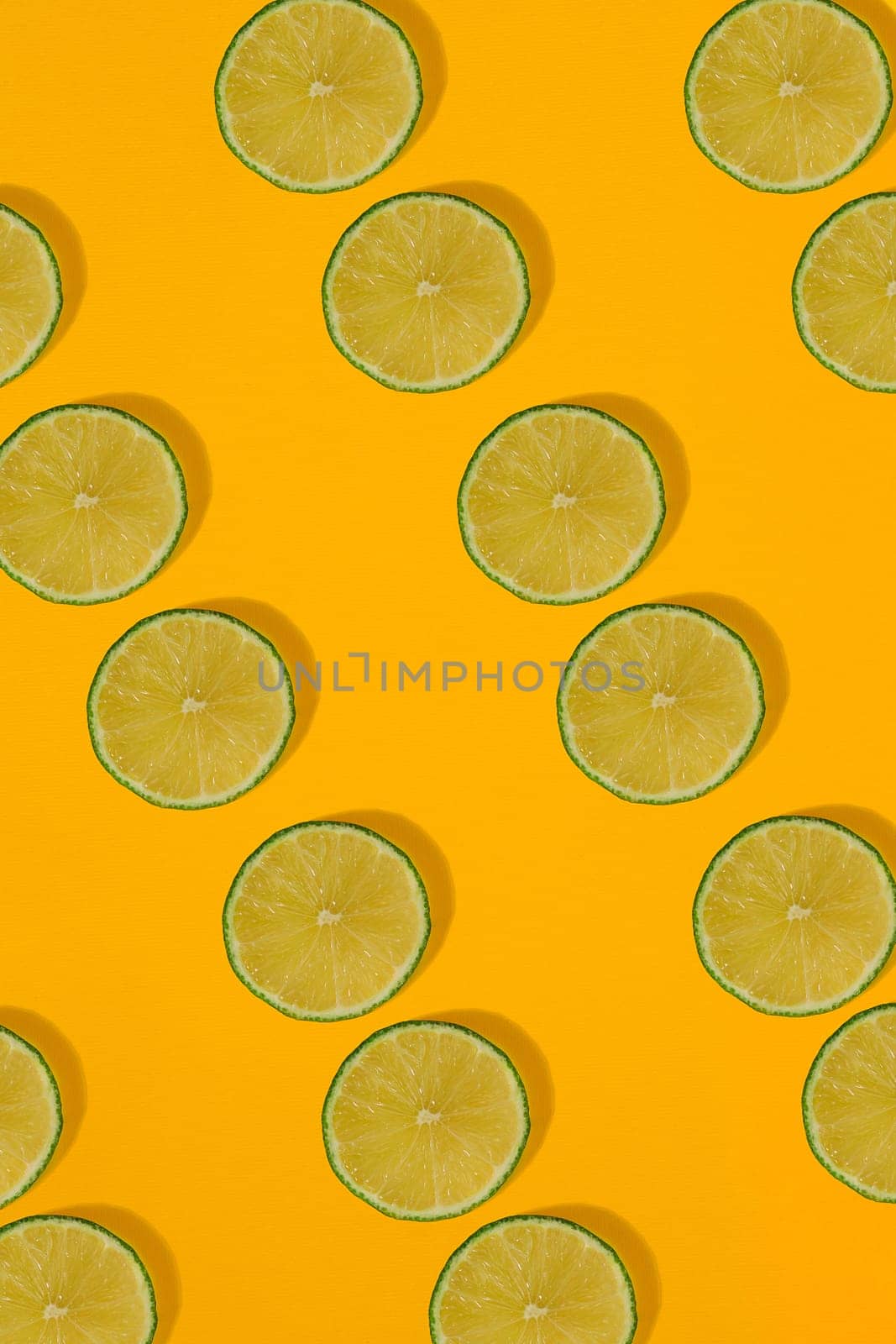 Lime pattern on yellow background. Minimal flat lay concept. by nazarovsergey
