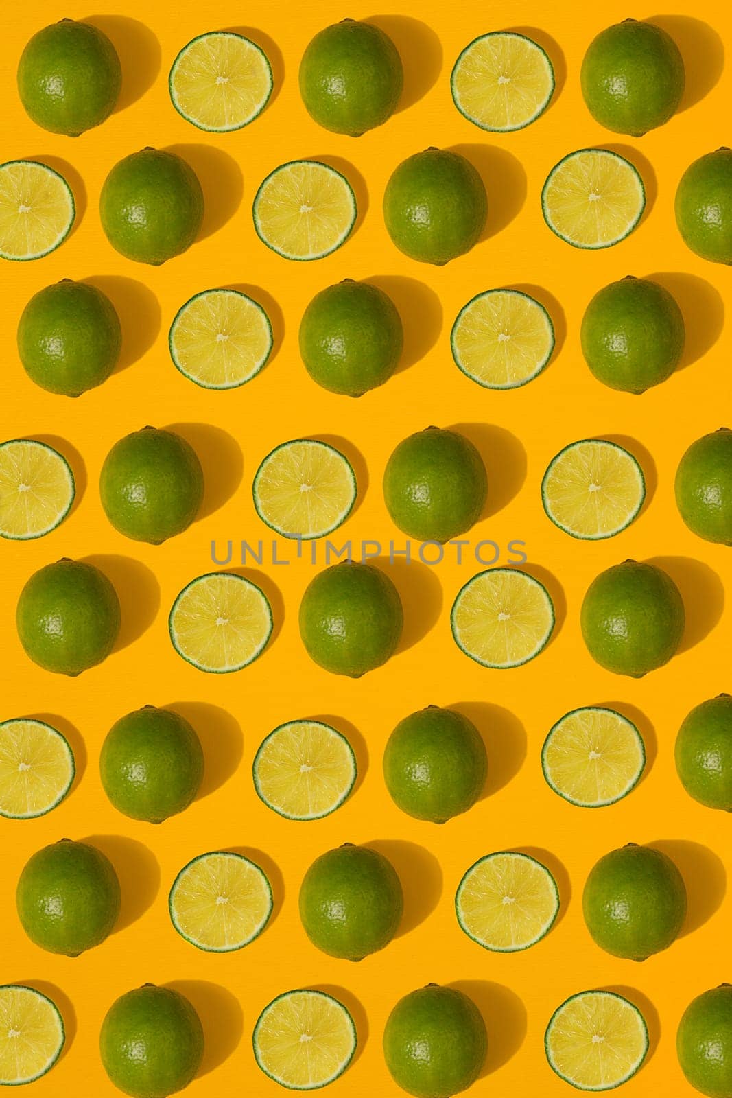 Lime pattern on yellow background. Minimal flat lay concept. by nazarovsergey