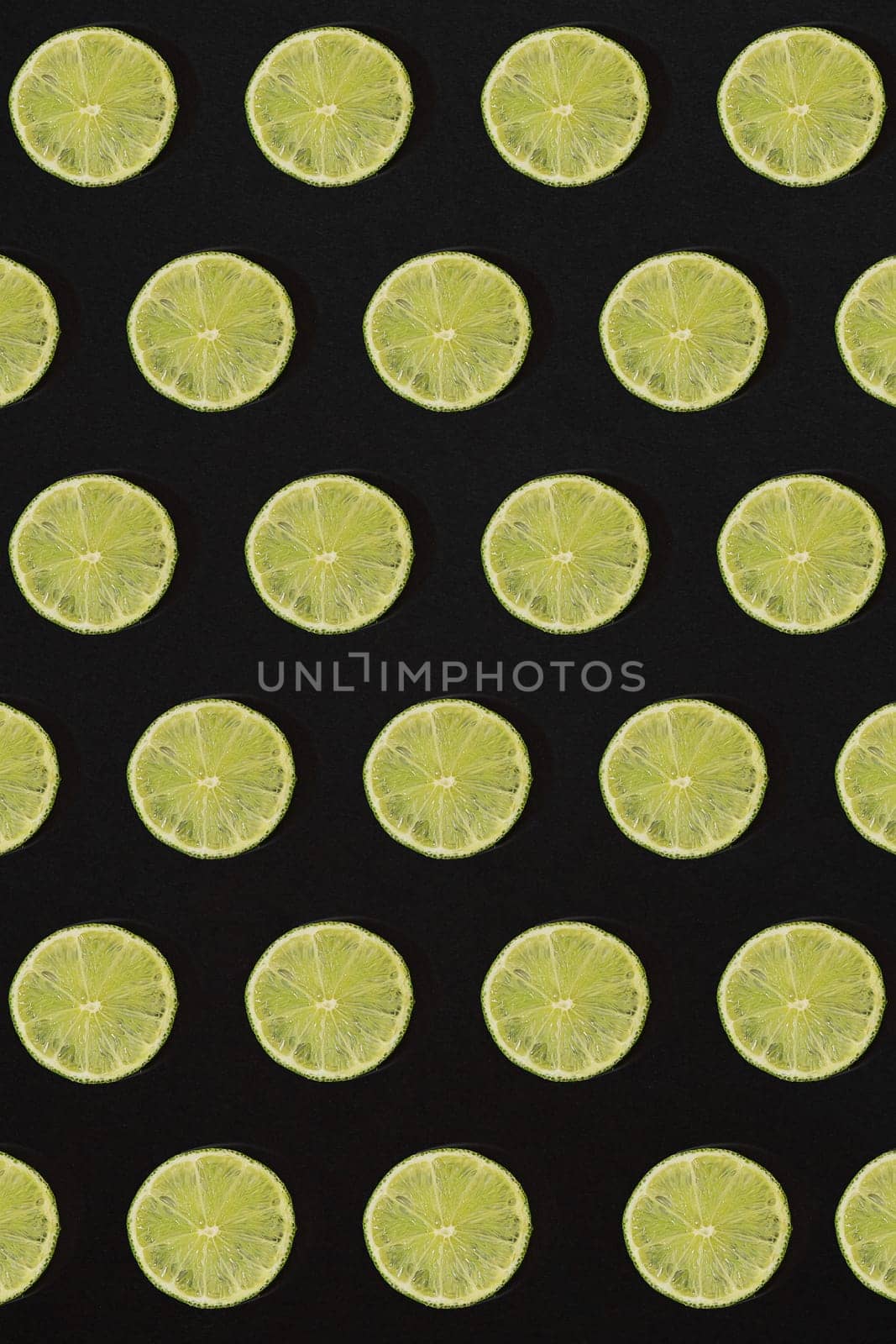 Lime pattern on black background. Minimal flat lay concept. by nazarovsergey