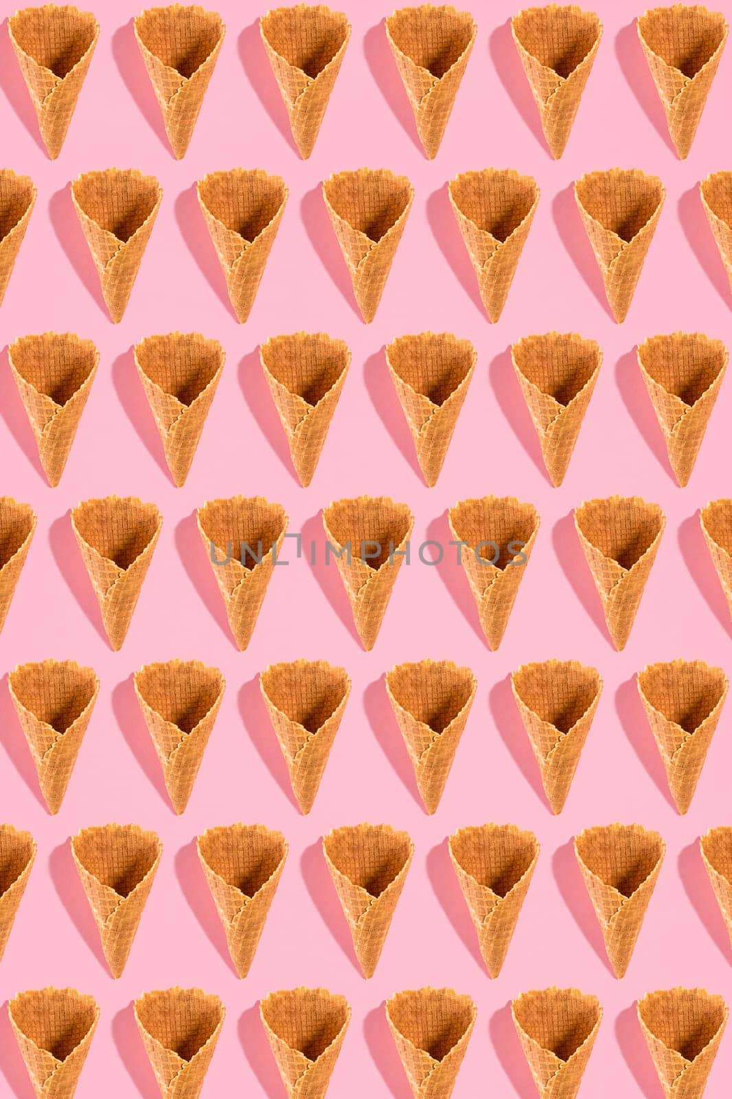 Sugar waffle cone for ice cream arranged in pattern on pink background. The image with copy space can be used as a background for the design of the confectionery menu by nazarovsergey