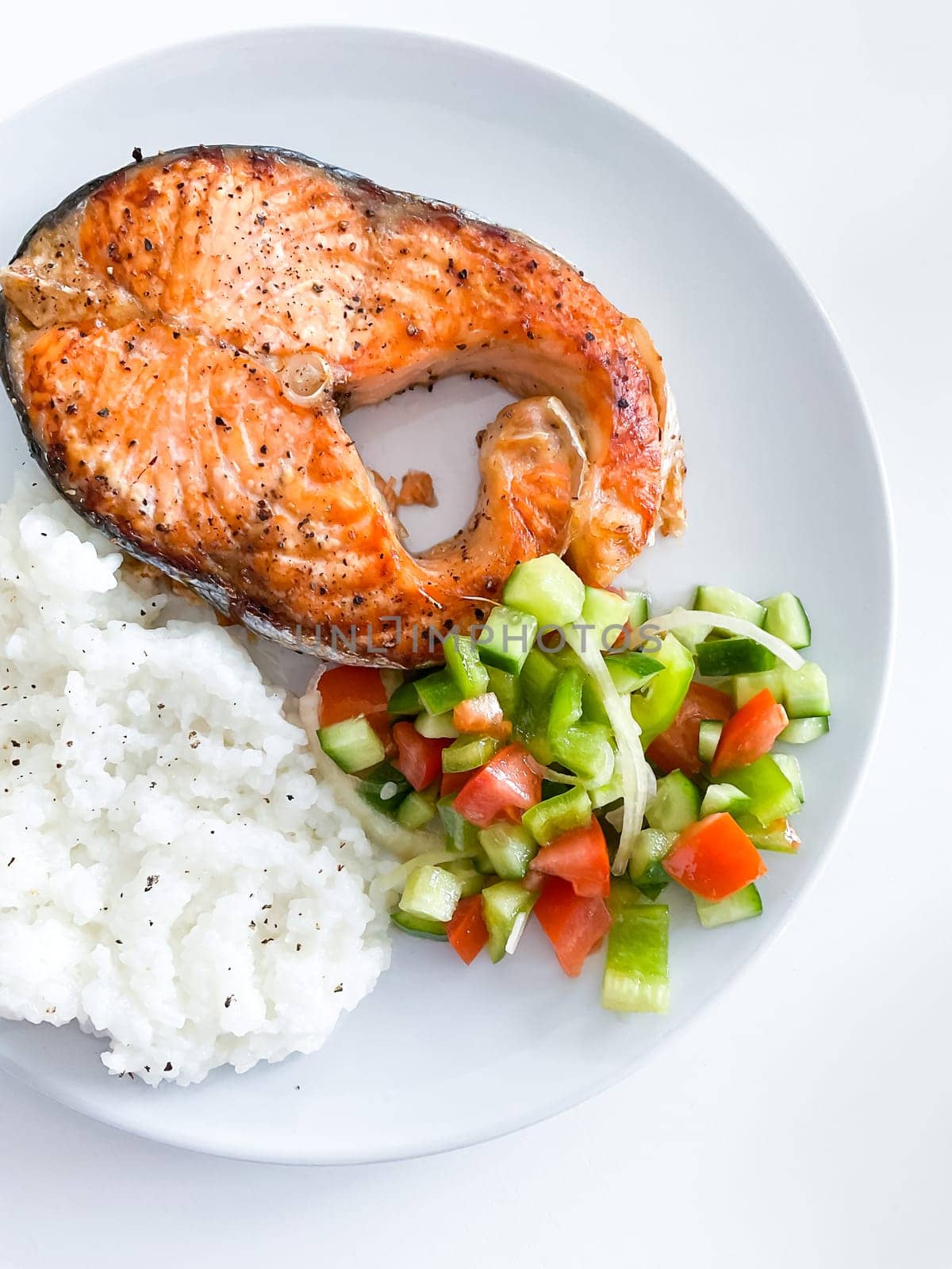 Healthy balanced meal lunch plate - baked salmon with rice and vegetables on a light background, top view