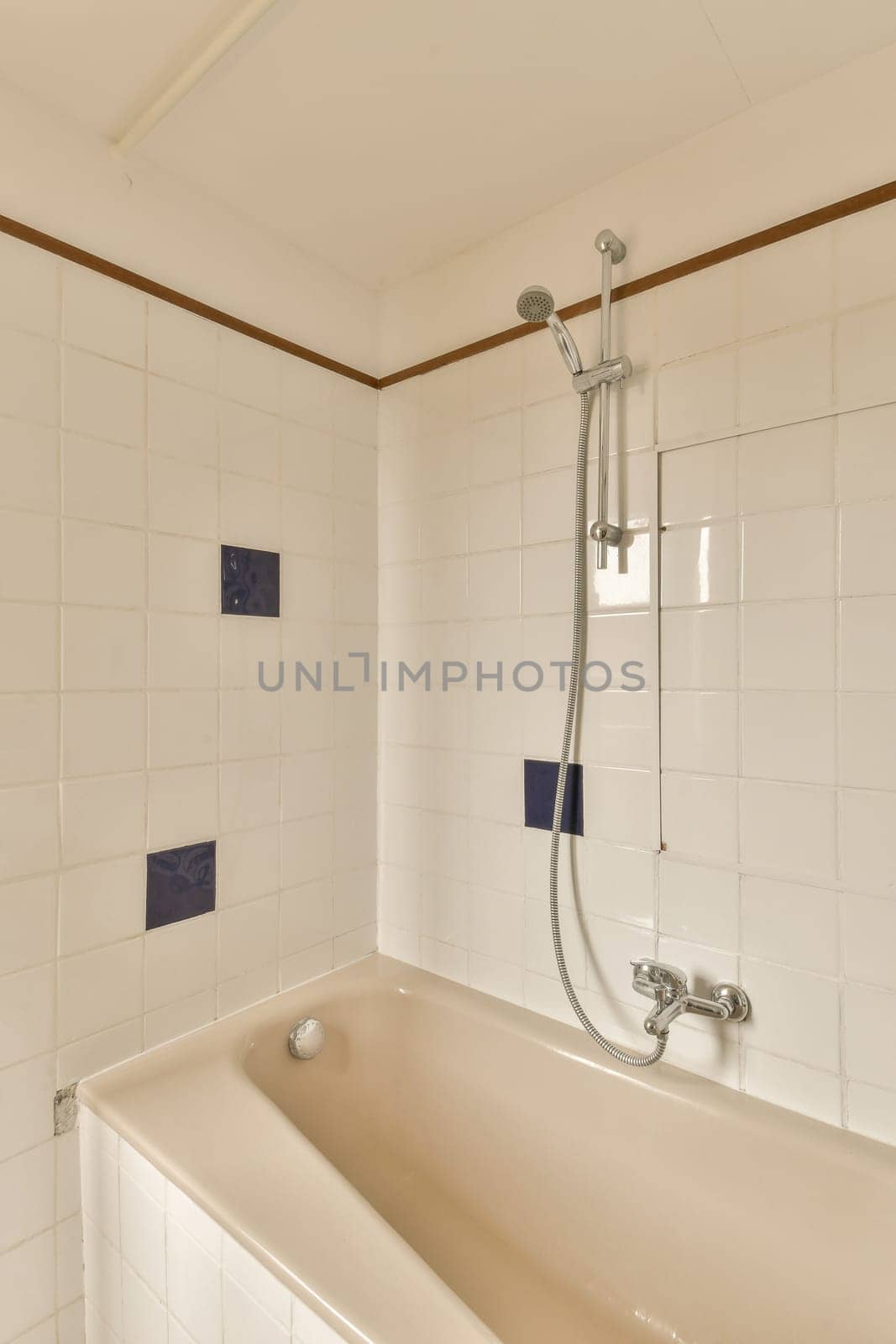 a bathroom with white tiles and wood trim around the tub, which has been used as a shower stall for people to use