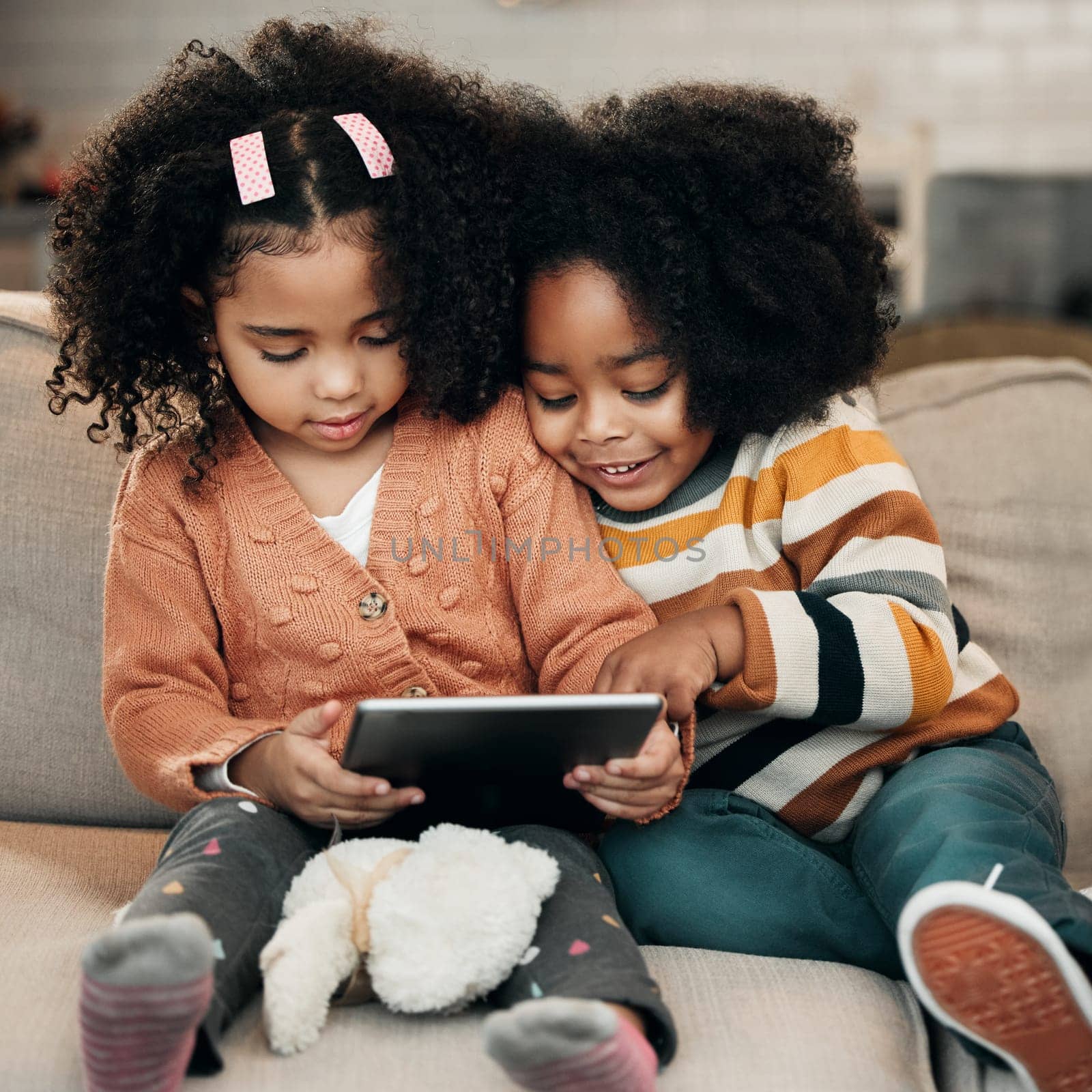 Happy children on sofa with tablet for online education, fun games and watch internet cartoon or video together. Biracial family kids on couch with digital technology, app or web for movie streaming by YuriArcurs