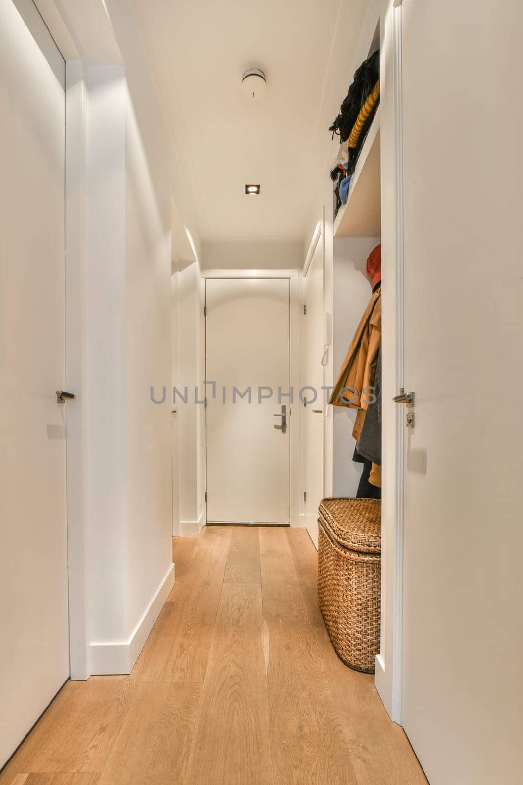 a hallway with white closets and a wood floor by casamedia