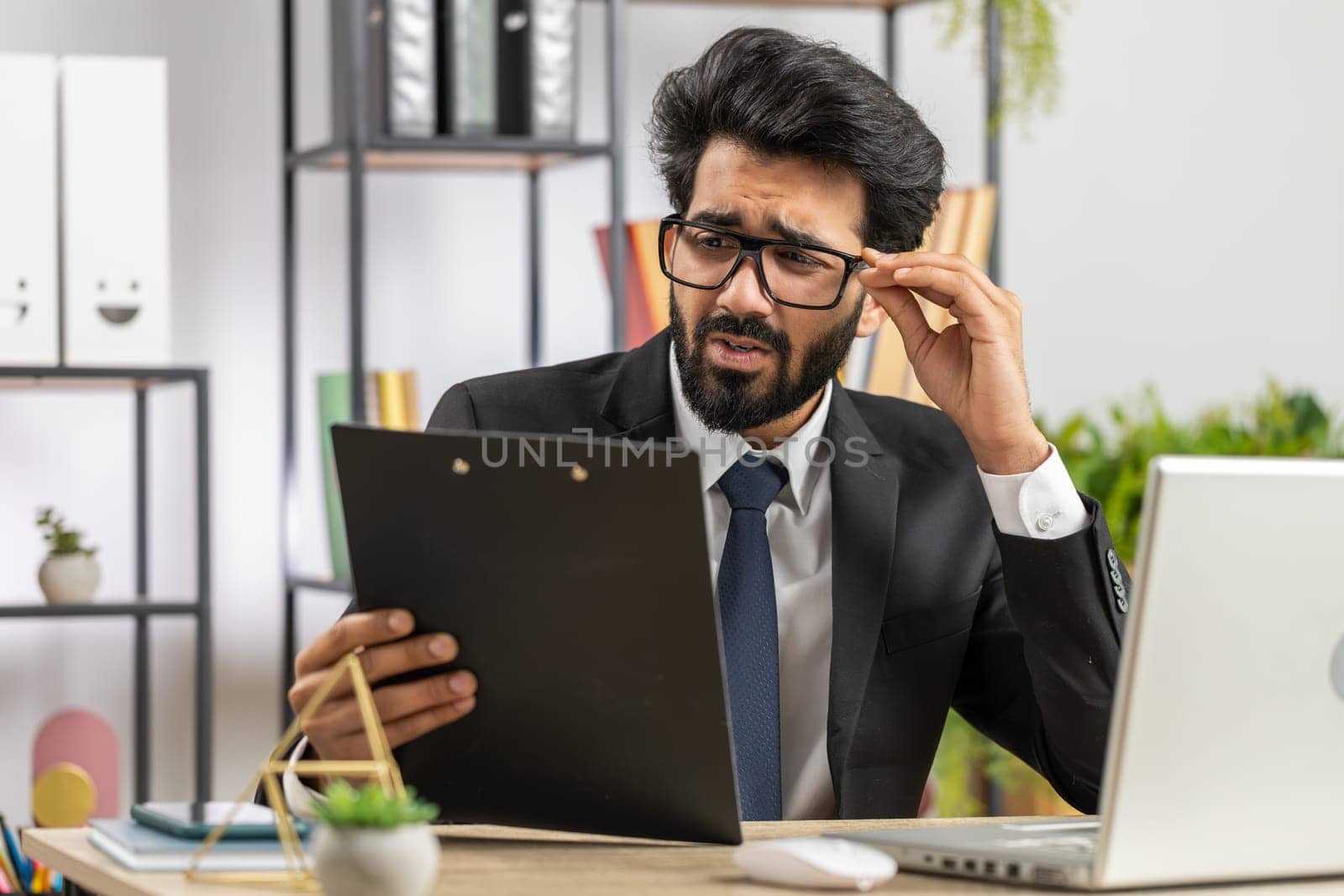 Tired indian businessman feeling worried about financial problem, stress at home office workplace. Indian freelancer broker man frustrated thinking of money debt, budget loss, bankruptcy. Overworking