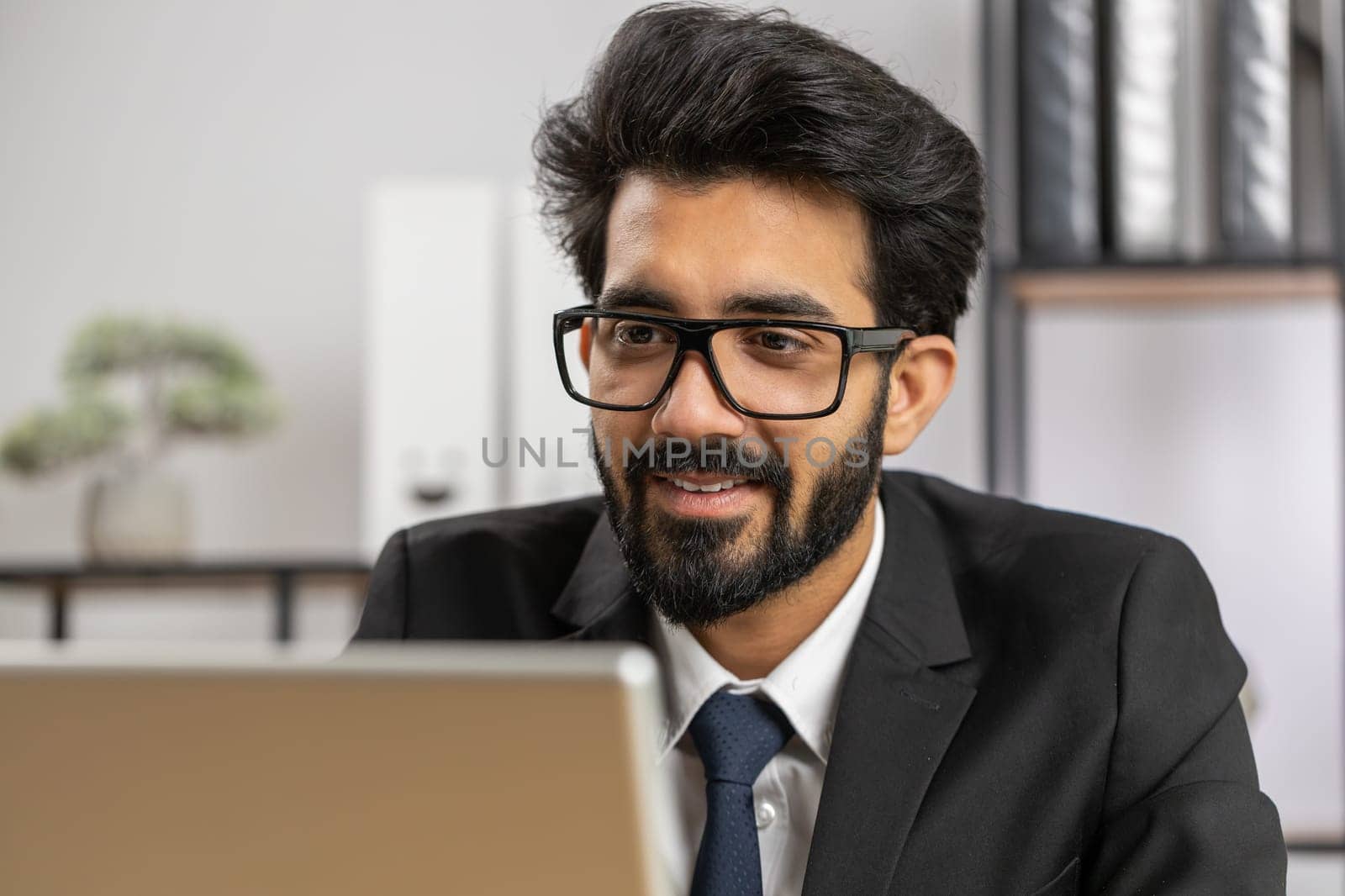 Close-up portrait indian bearded businessman face freelancer at home office workplace working on laptop computer. Manager freelancer indian man works on notebook send messages makes online purchases