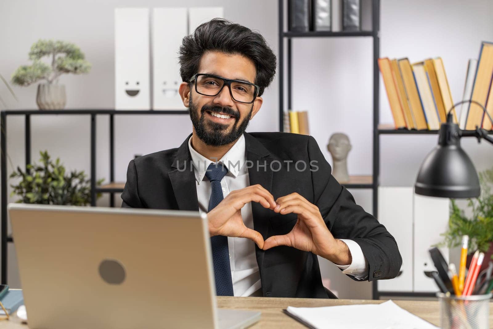 I love you. Indian business man makes symbol of love, showing heart sign to camera, express romantic feelings, express sincere positive feelings at home office workplace. Charity, gratitude, donation