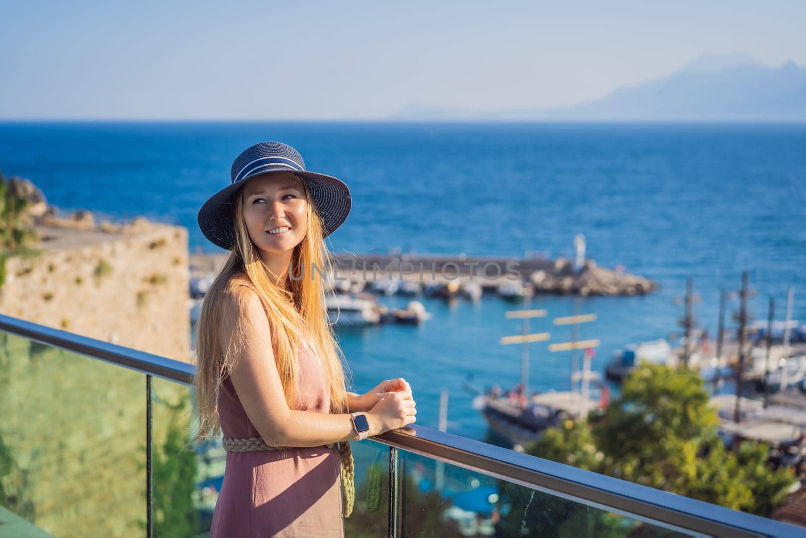 Woman tourist in Old town Kaleici in Antalya. Turkiye. Panoramic view of Antalya Old Town port, Taurus mountains and Mediterrranean Sea, Turkey.