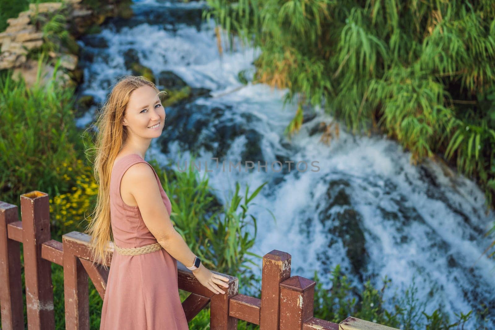 Beautiful woman with long hair on the background of Duden waterfall in Antalya. Famous places of Turkey. Lower Duden Falls drop off a rocky cliff falling from about 40 m into the Mediterranean Sea in amazing water clouds. Tourism and travel destination photo in Antalya, Turkey. Turkiye.