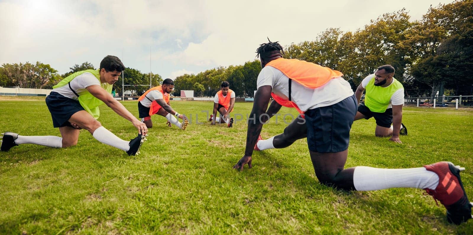 Sports, training and men outdoor for rugby on grass field with diversity team stretching as warm up. Athlete group together for fitness, exercise and workout for professional sport or teamwork energy by YuriArcurs