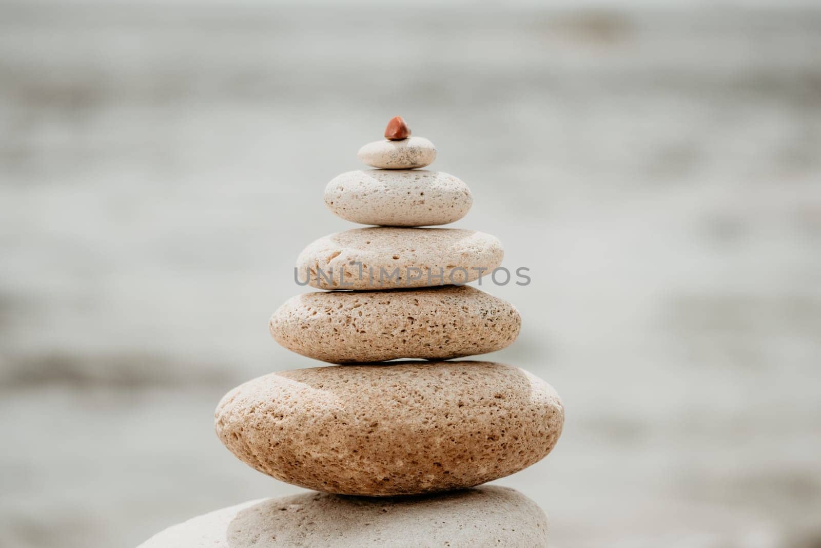 Pyramid stones on the seashore with warm sunset on the sea background. Happy holidays. Pebble beach, calm sea, travel destination. Concept of happy vacation on the sea, meditation, spa, calmness.