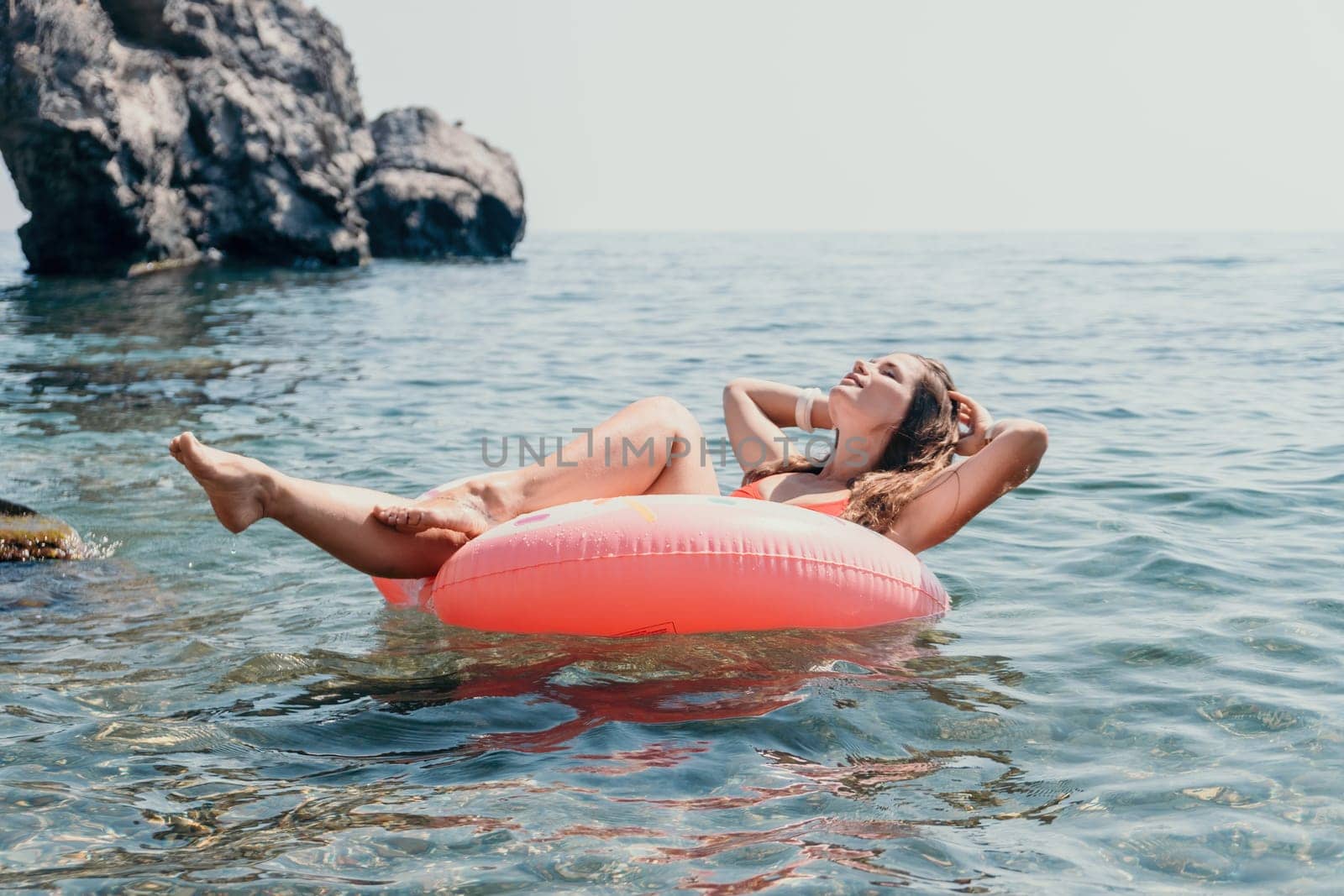 Woman summer sea. Happy woman swimming with inflatable donut on the beach in summer sunny day, surrounded by volcanic mountains. Summer vacation concept. by panophotograph