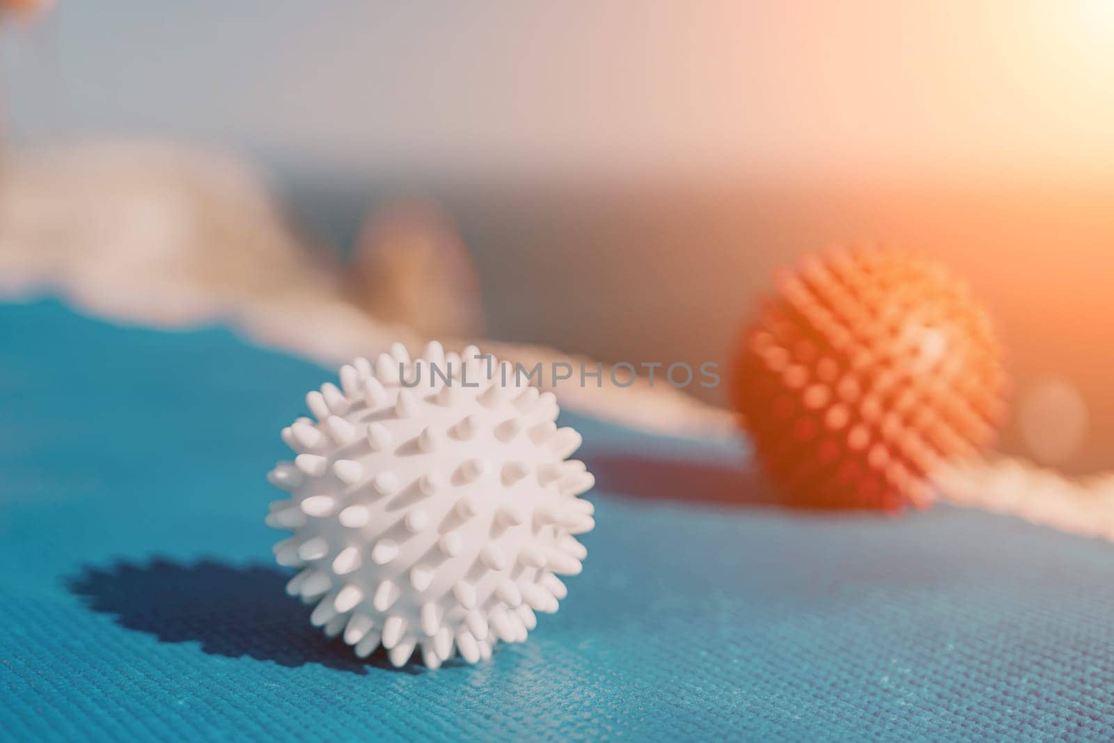 Woman sea pilates. Red and white massage balls are placed on a yoga mat, with the sea in the background. Healthy lifestyle, harmony and meditation. by panophotograph