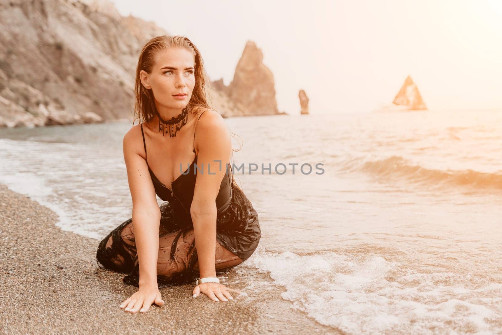 Woman summer travel sea. Happy tourist in black dress enjoy taking picture outdoors for memories. Woman traveler posing on sea beach surrounded by volcanic mountains, sharing travel adventure journey by panophotograph