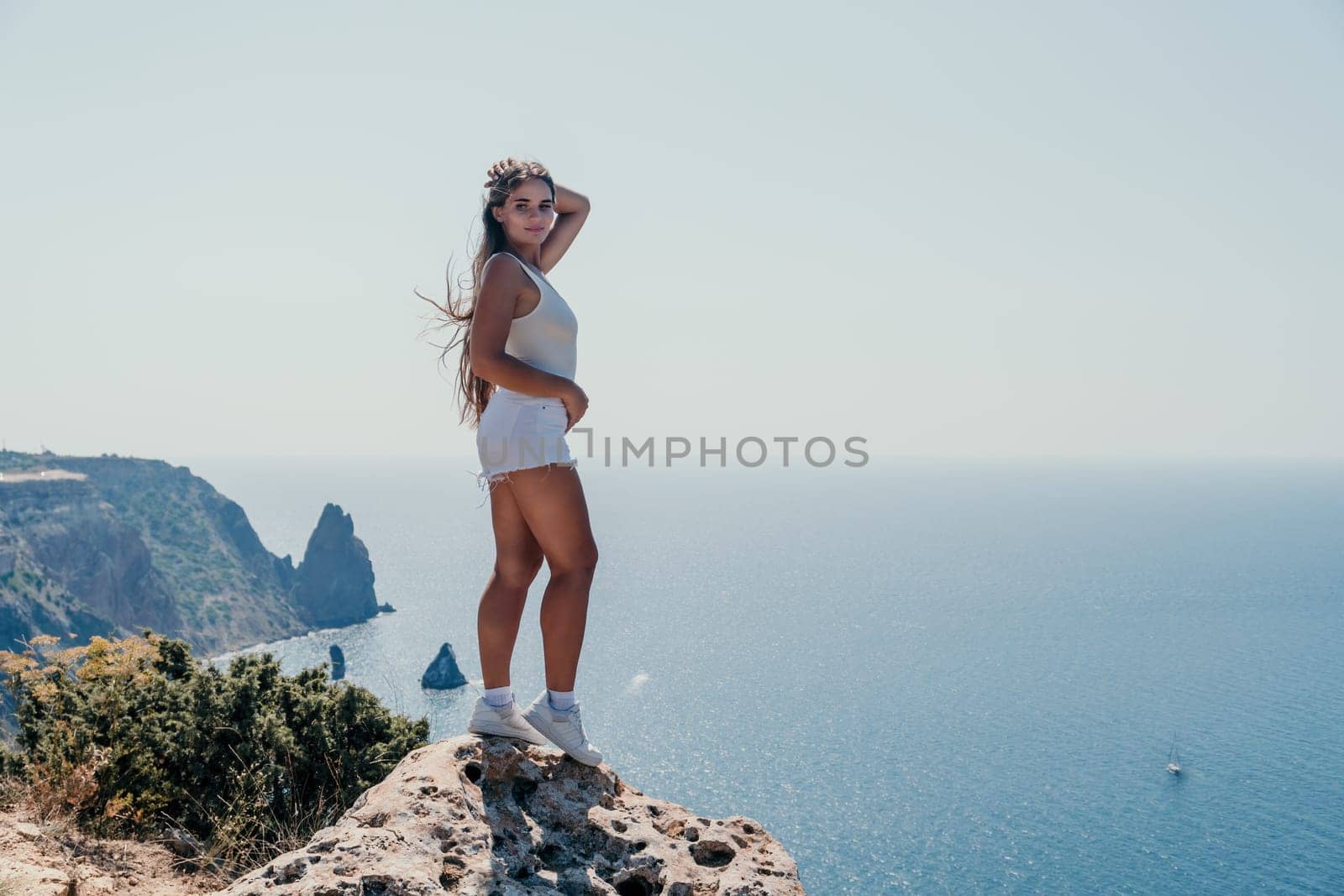 Woman travel sea. Young Happy woman in a long red dress posing on a beach near the sea on background of volcanic rocks, like in Iceland, sharing travel adventure journey