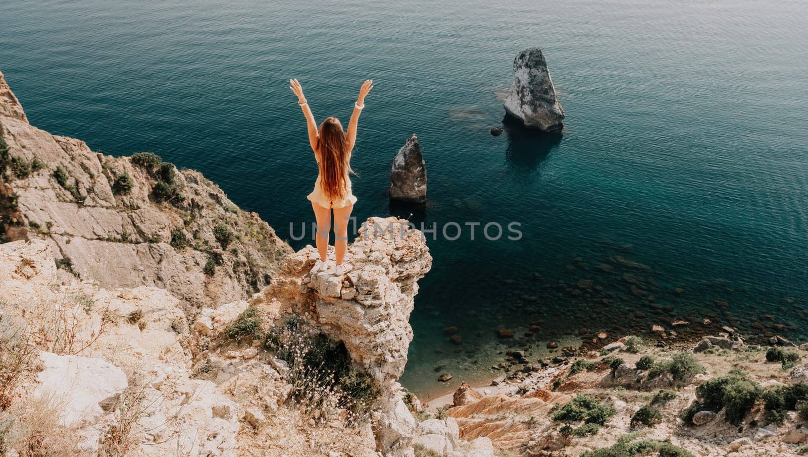 Woman travel sea. Happy tourist taking picture outdoors for memories. Woman traveler looks at the edge of the cliff on the sea bay of mountains, sharing travel adventure journey.