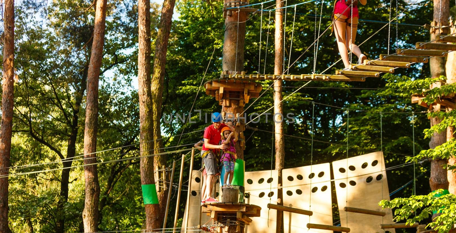 male instructor helps the child on the rope road in the training camp