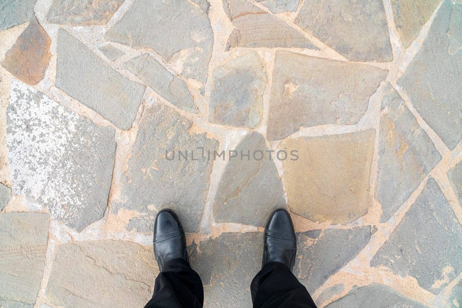 the feet of a man in shoes on the paving slabs. photo