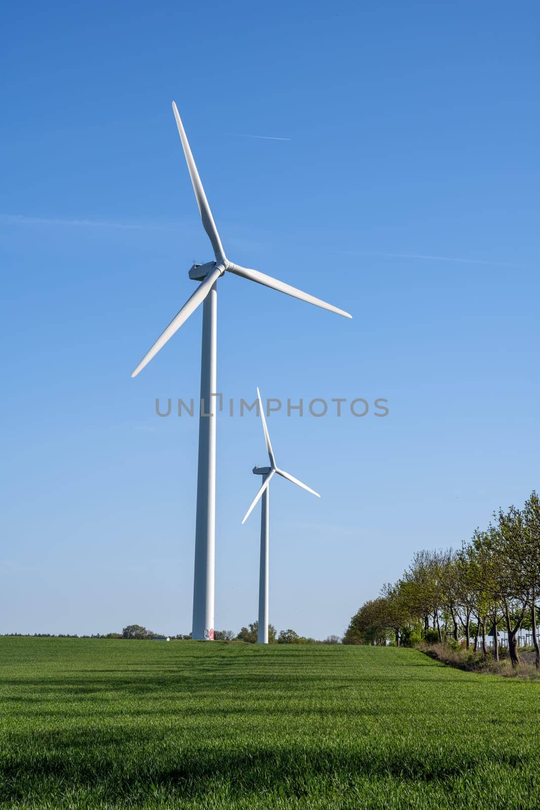 Modern wind turbines in front of a blue sky by elxeneize