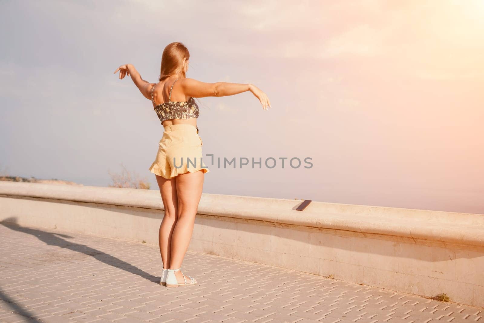 silhouette of a happy woman who dances, spins and raises her hands to the sky. A woman is enjoying a beautiful summer day.