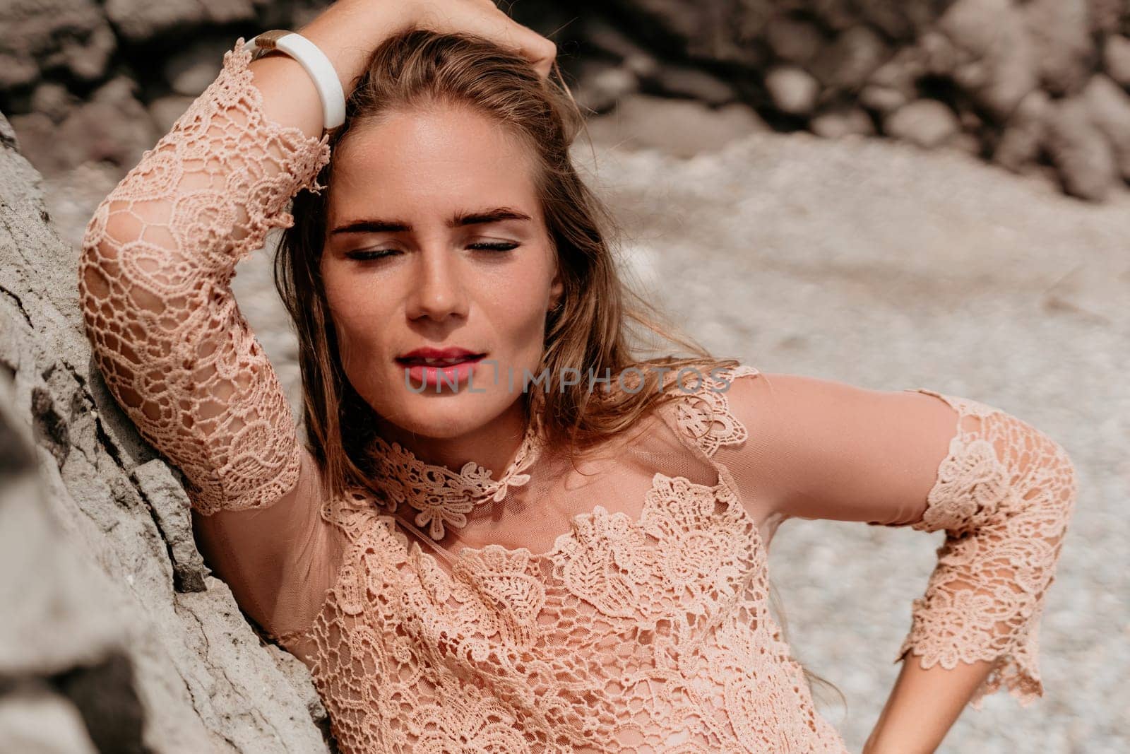 Woman summer travel sea. Happy tourist in beige dress enjoy taking picture outdoors for memories. Woman traveler posing on the beach surrounded by volcanic mountains, sharing travel adventure journey by panophotograph