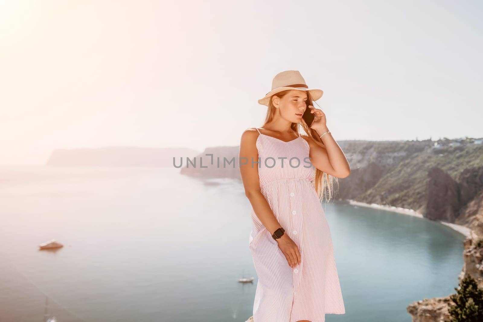 Digital nomad, Business woman working on laptop by the sea. Pretty lady typing on computer by the sea at sunset, makes a business transaction online from a distance. Freelance remote work on vacation